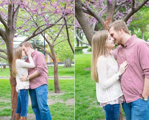 engaged couple kisses under blooming tree