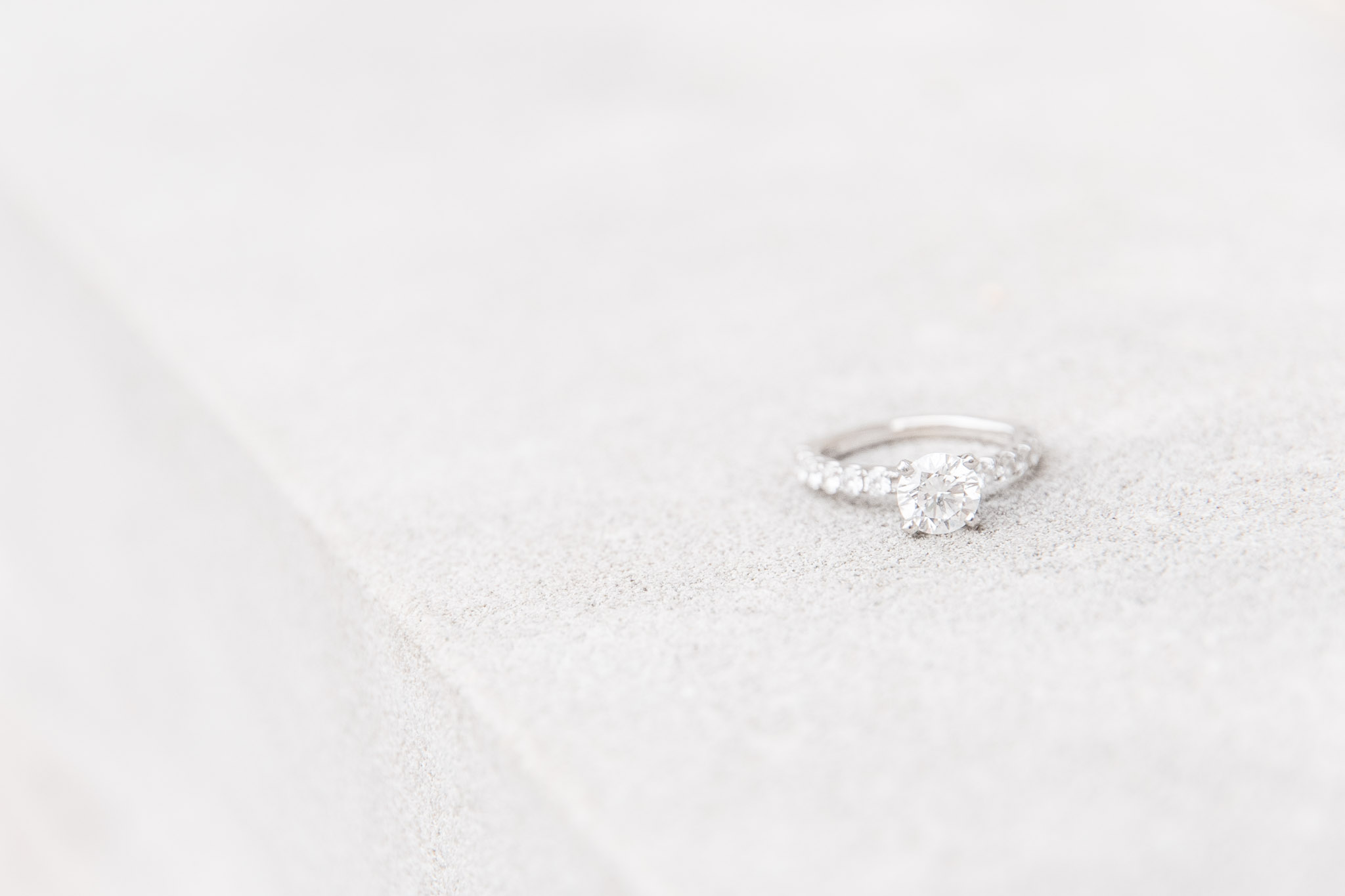 Engagement ring sits on concrete background.