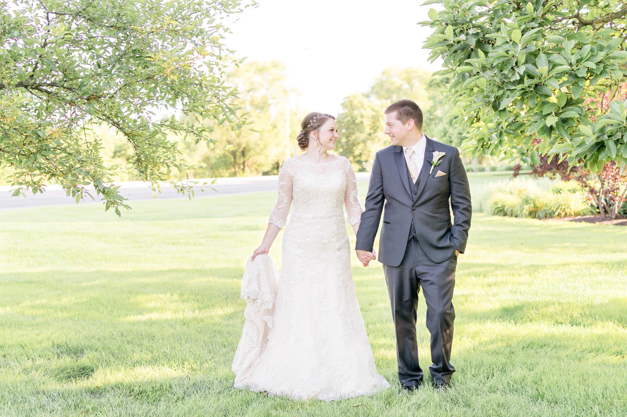 Bride and groom walk across lawn after Indianapolis wedding