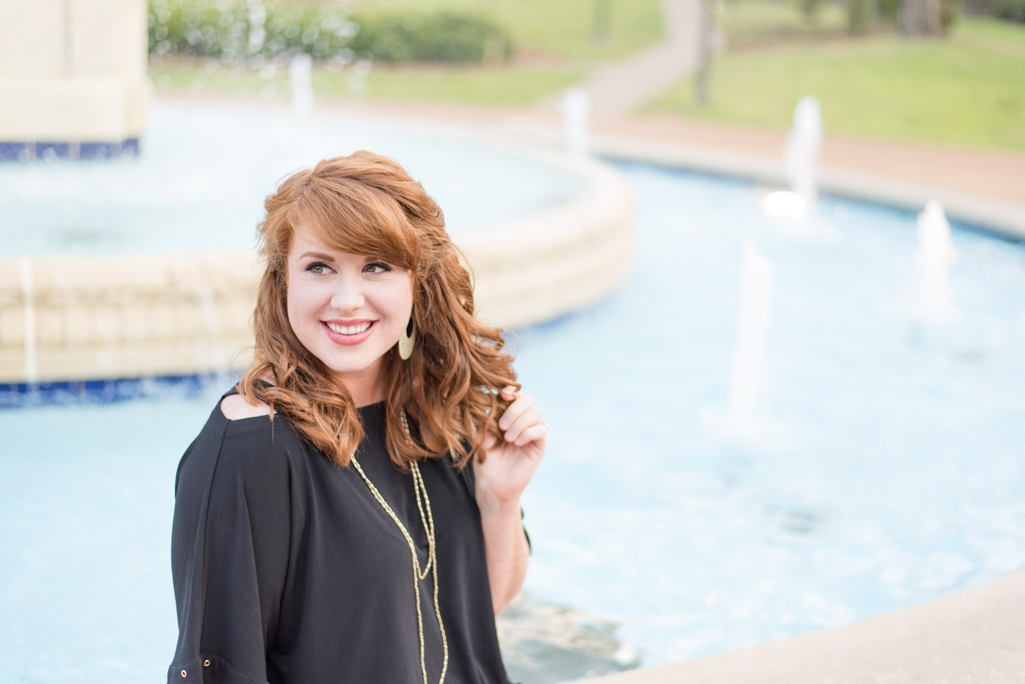 Senior smiles while sitting on UNA fountain