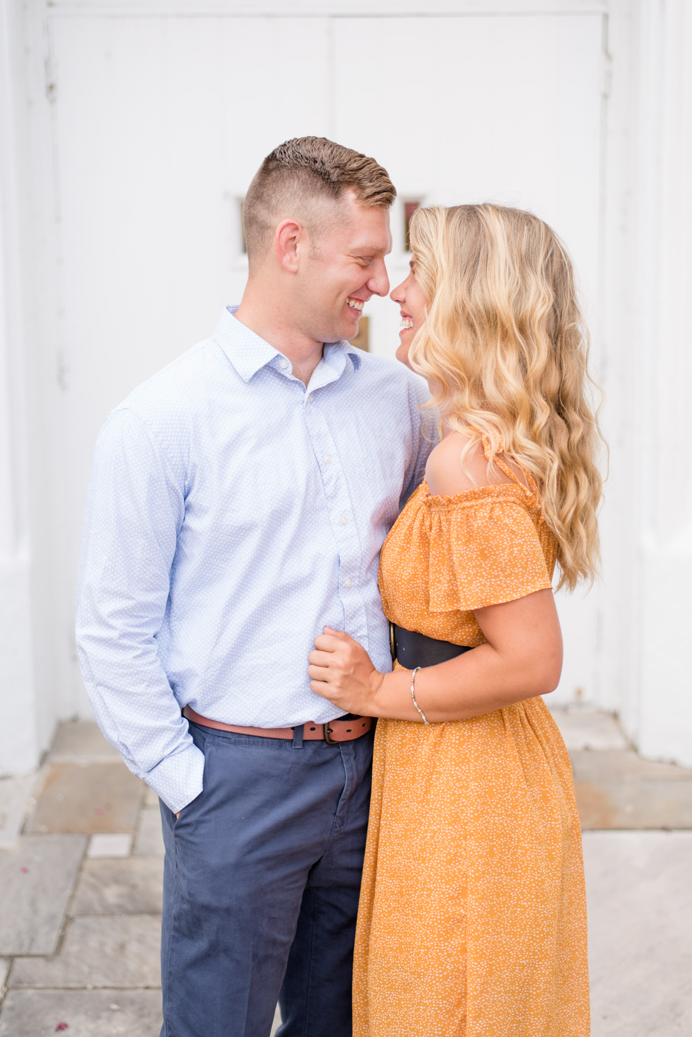 Bride and Groom laugh in front of white door. 