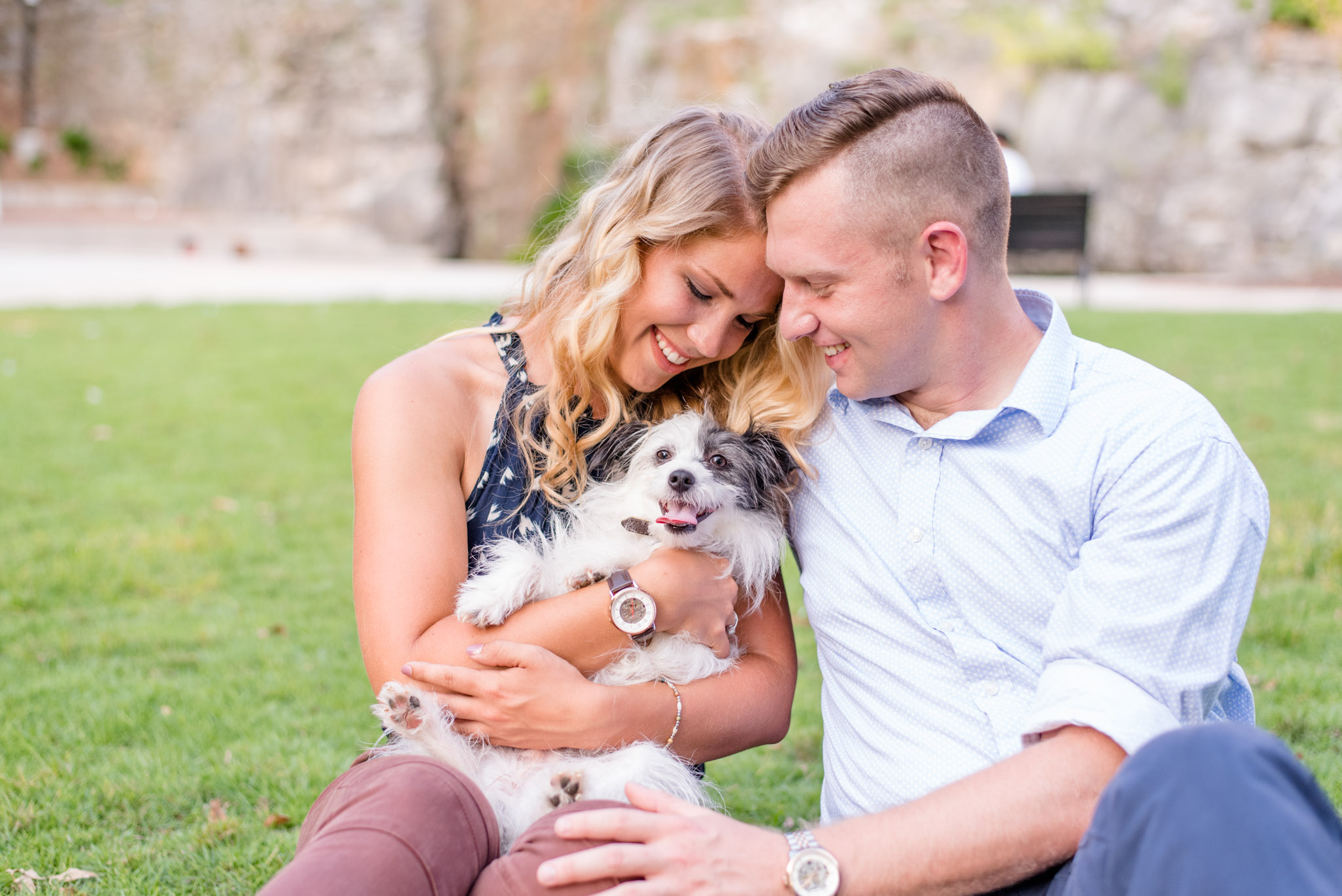 Engaged couple plays with dog.