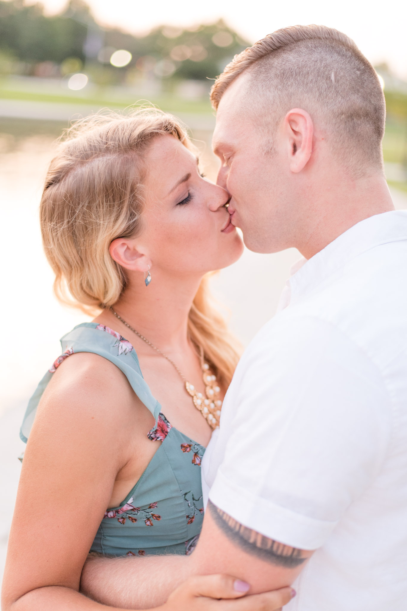 Alabama Engaged couple kisses next to lake at sunset.