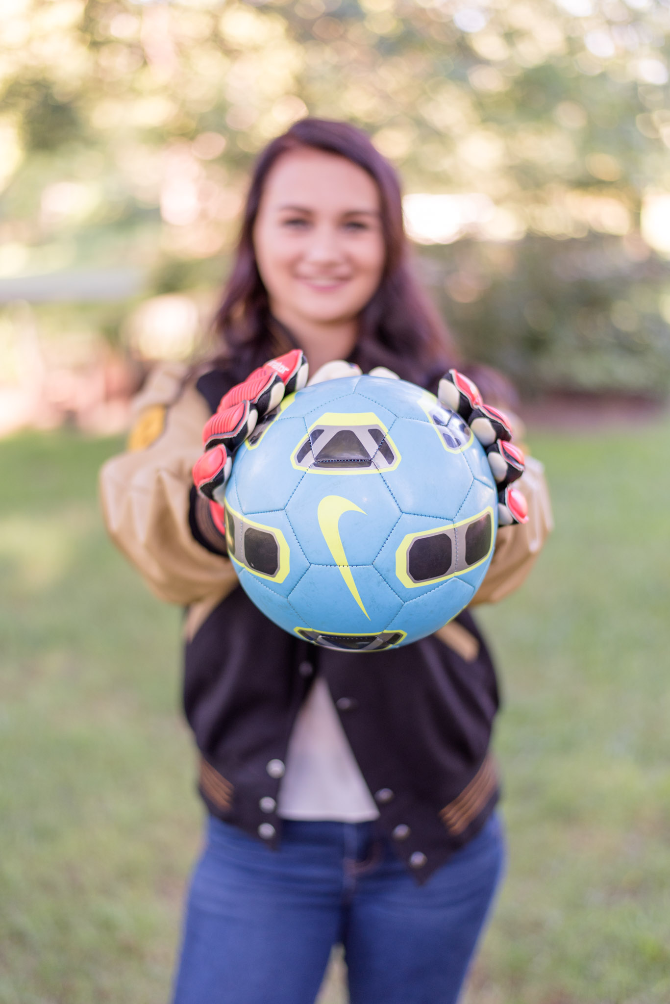 High school senior holds soccer ball.