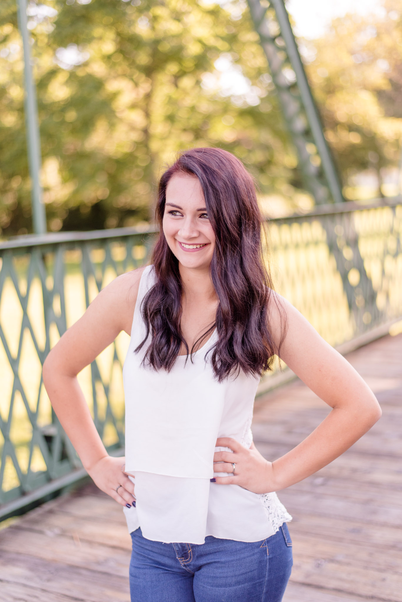 High school senior smiles while taking pictuers on bridge.