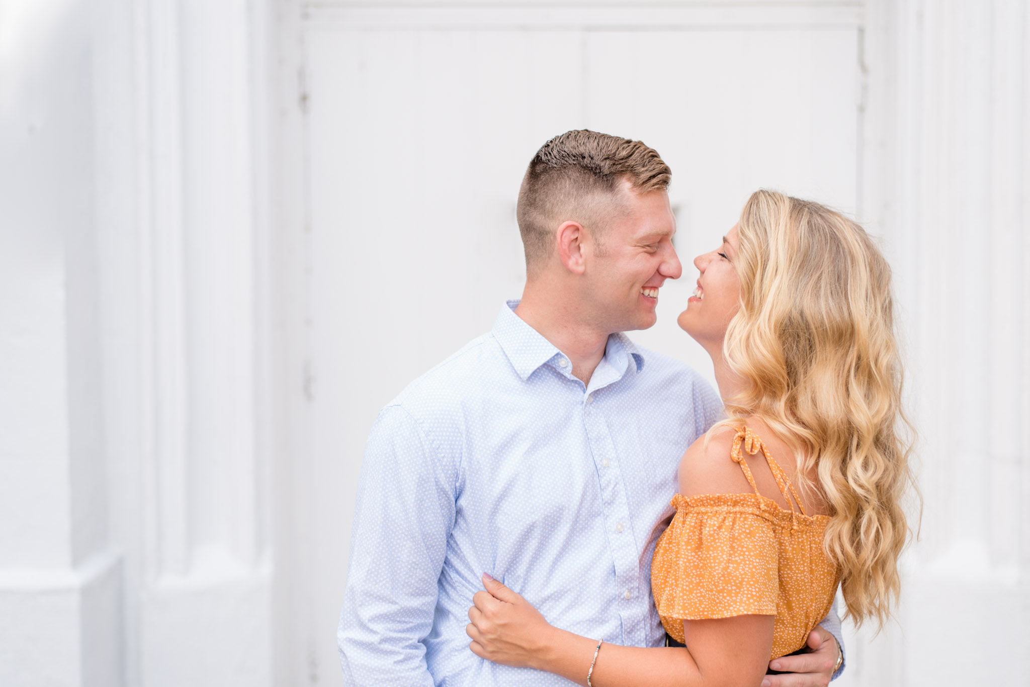 Alabama couple laughs in front of white door. 