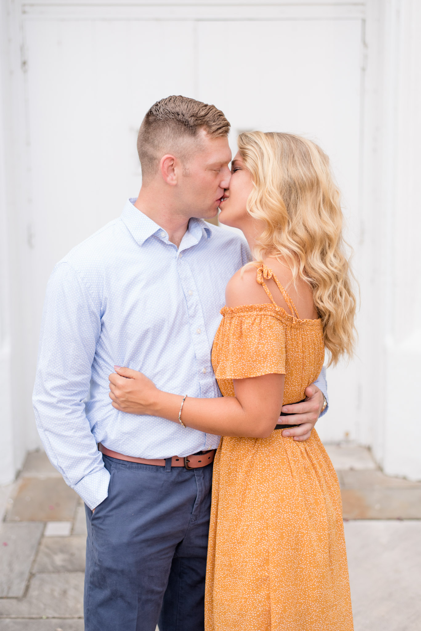 Huntsville Couple kisses in front of white door.