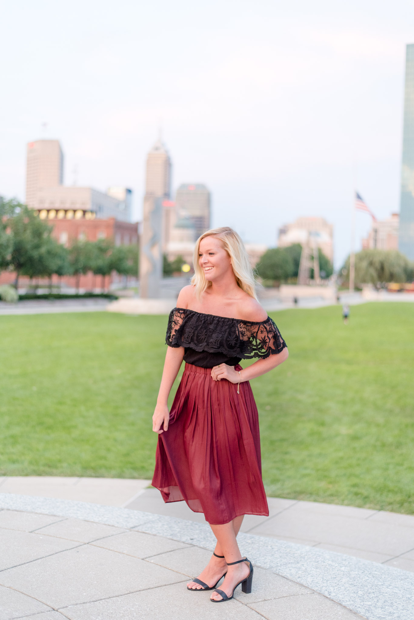 College senior laughs off camera with cityscape behind her.