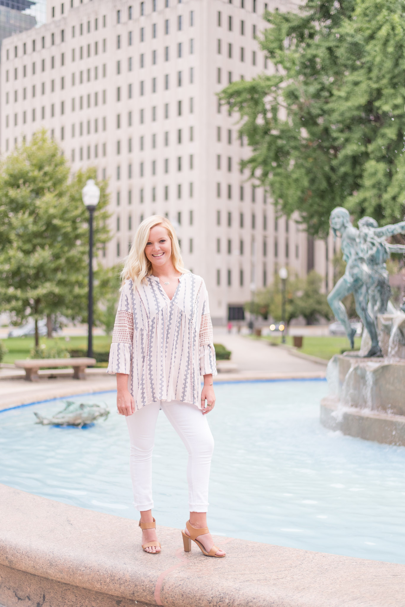 Senior stands on fountain in downtown Indianapolis.