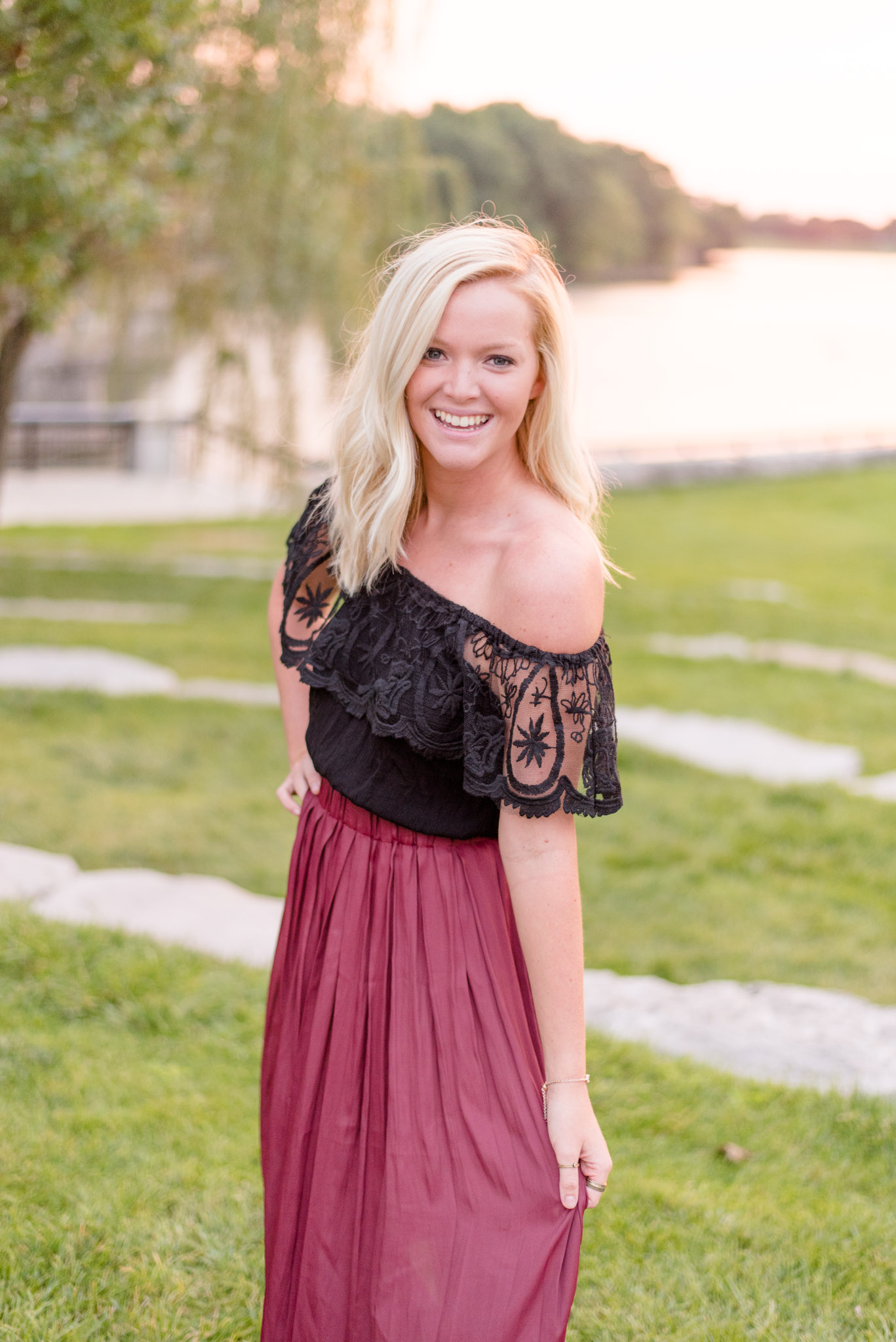 Senior laughs in front of White River at sunset.