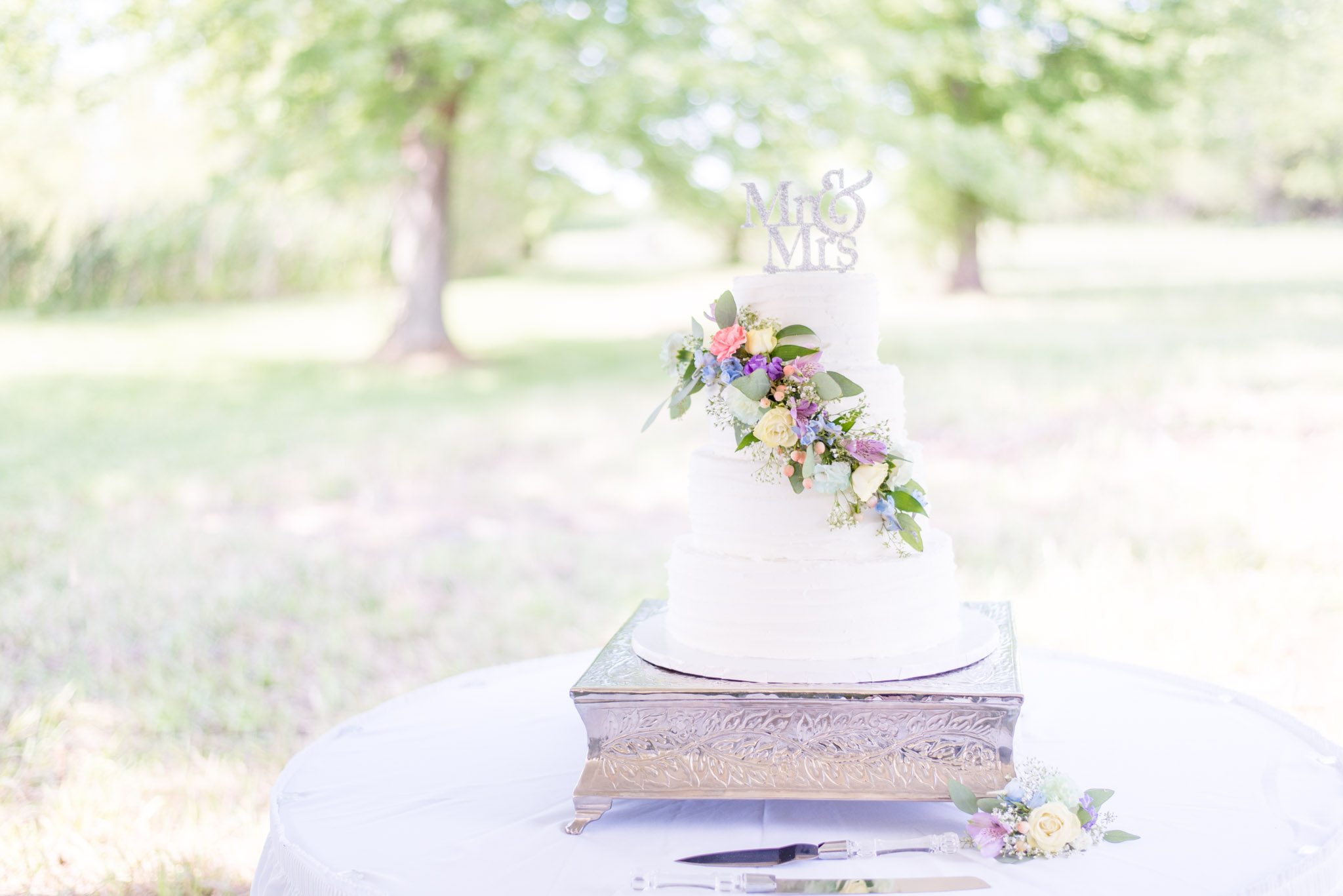 Wedding Cake Sits on Silver Stand