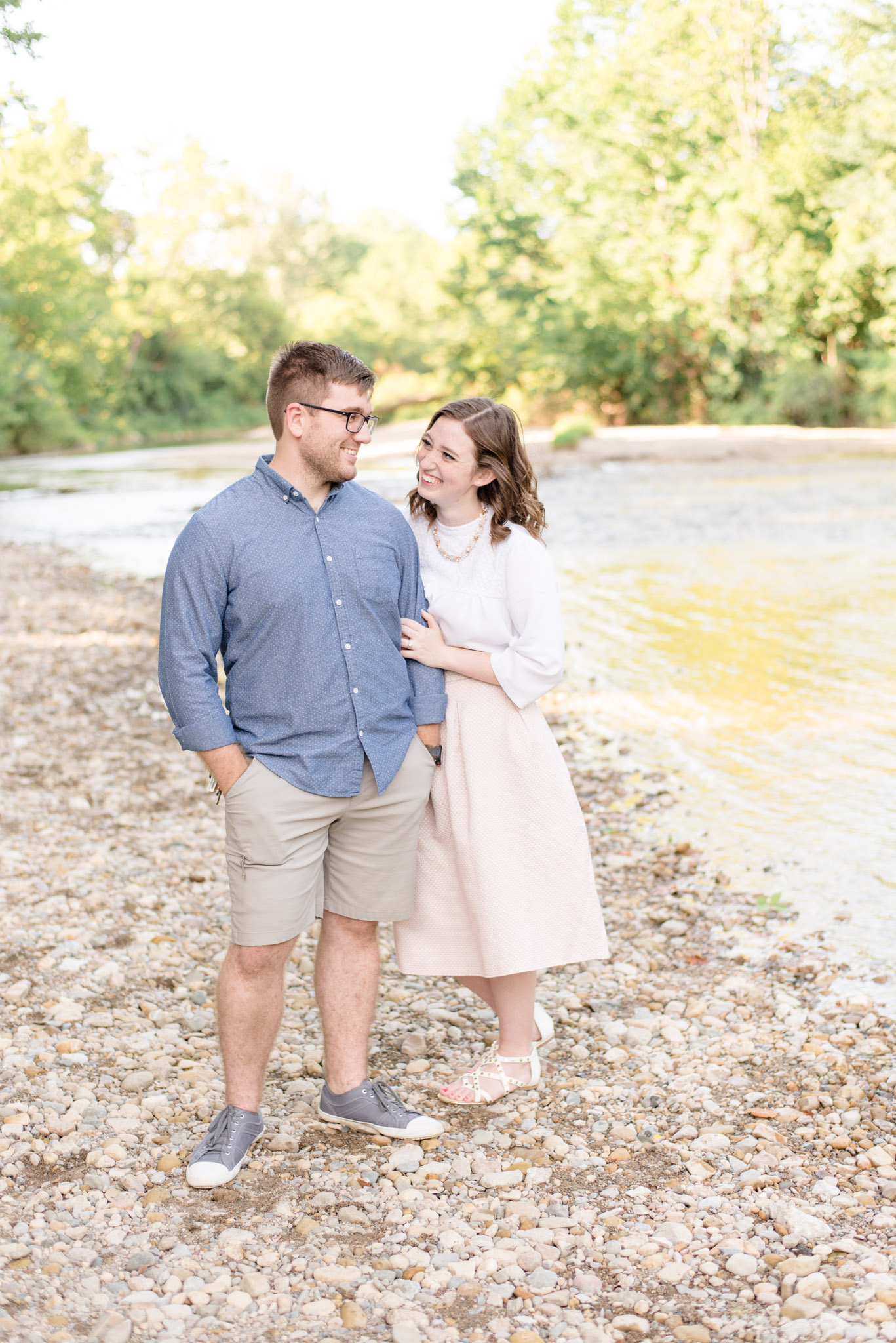 Indianapolis couple smiles at each other next to river.