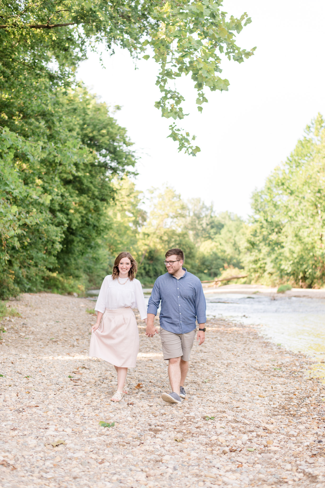 Indianapolis couple smiles as they walk by river.