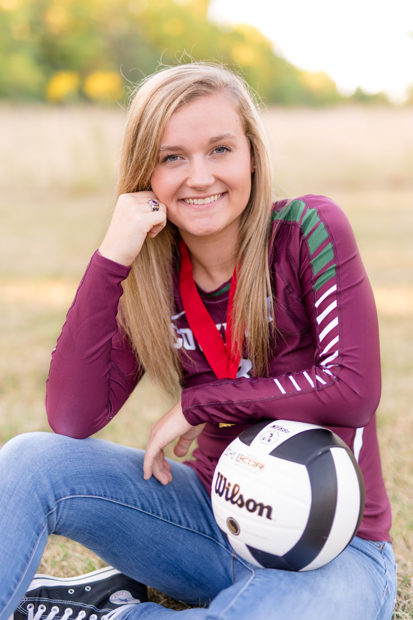 High School senior sits with volleyball for pictures