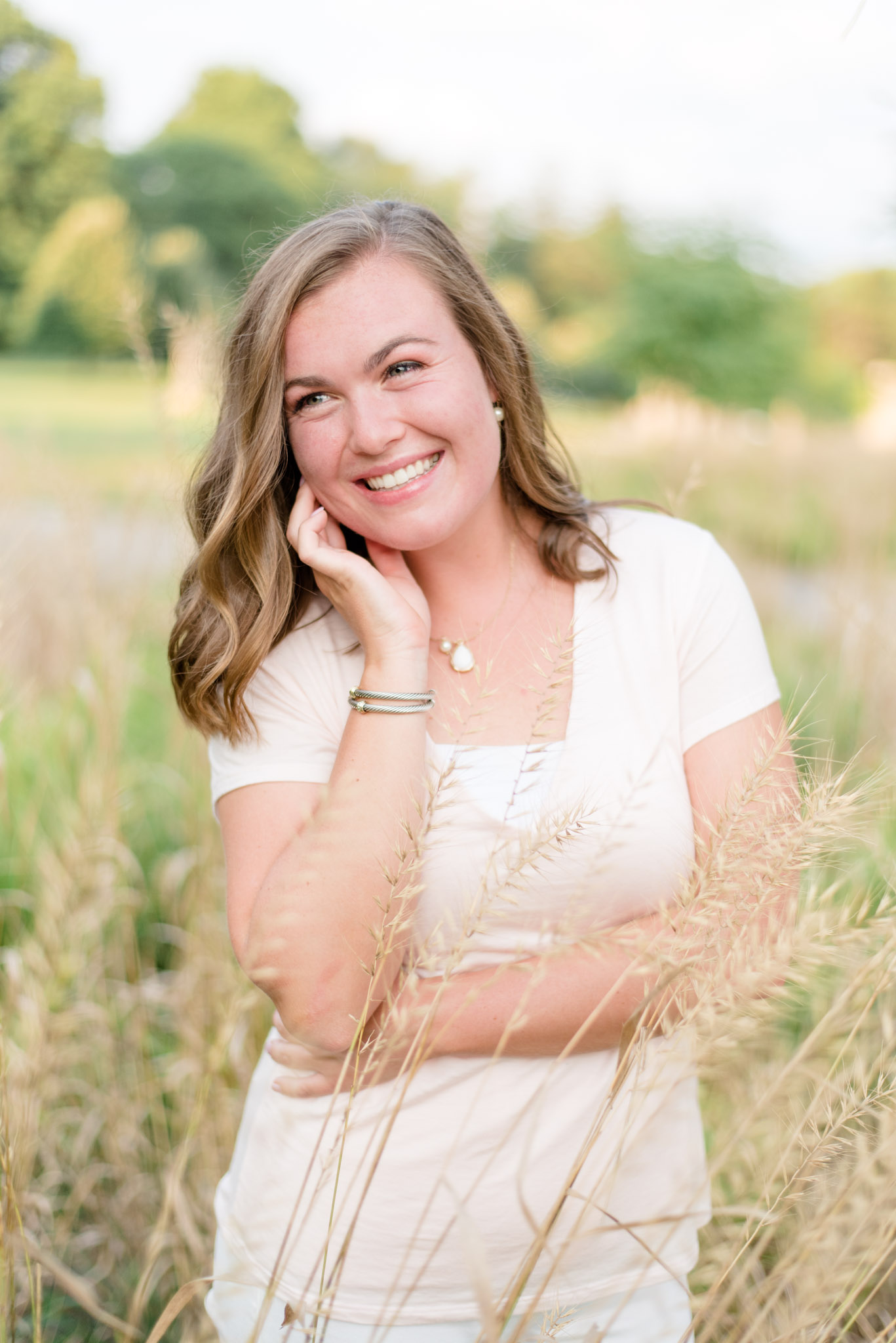 Girl smiles in tall grass while looking off camera.