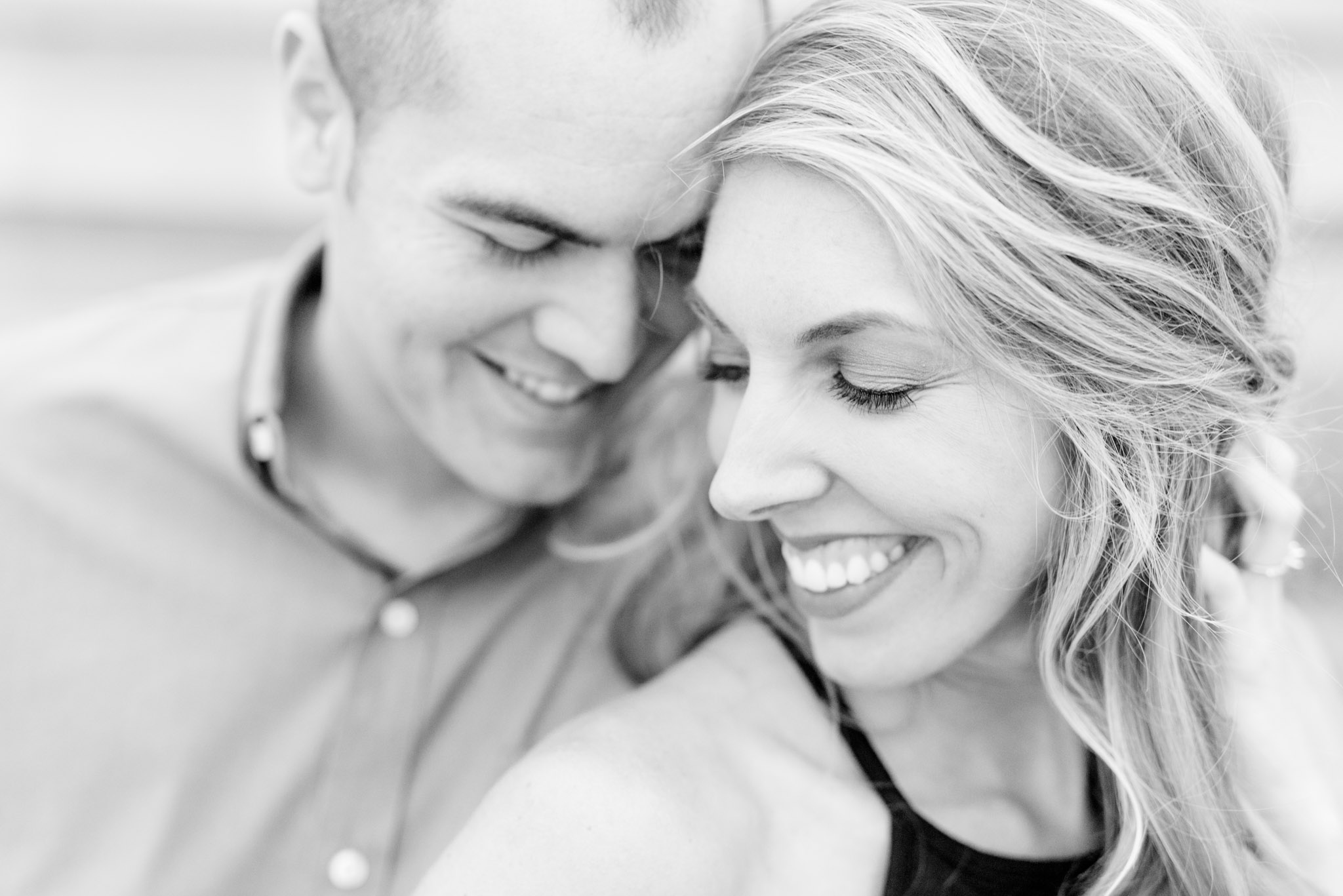 Engaged bride and groom smiles while leaning foreheads together.