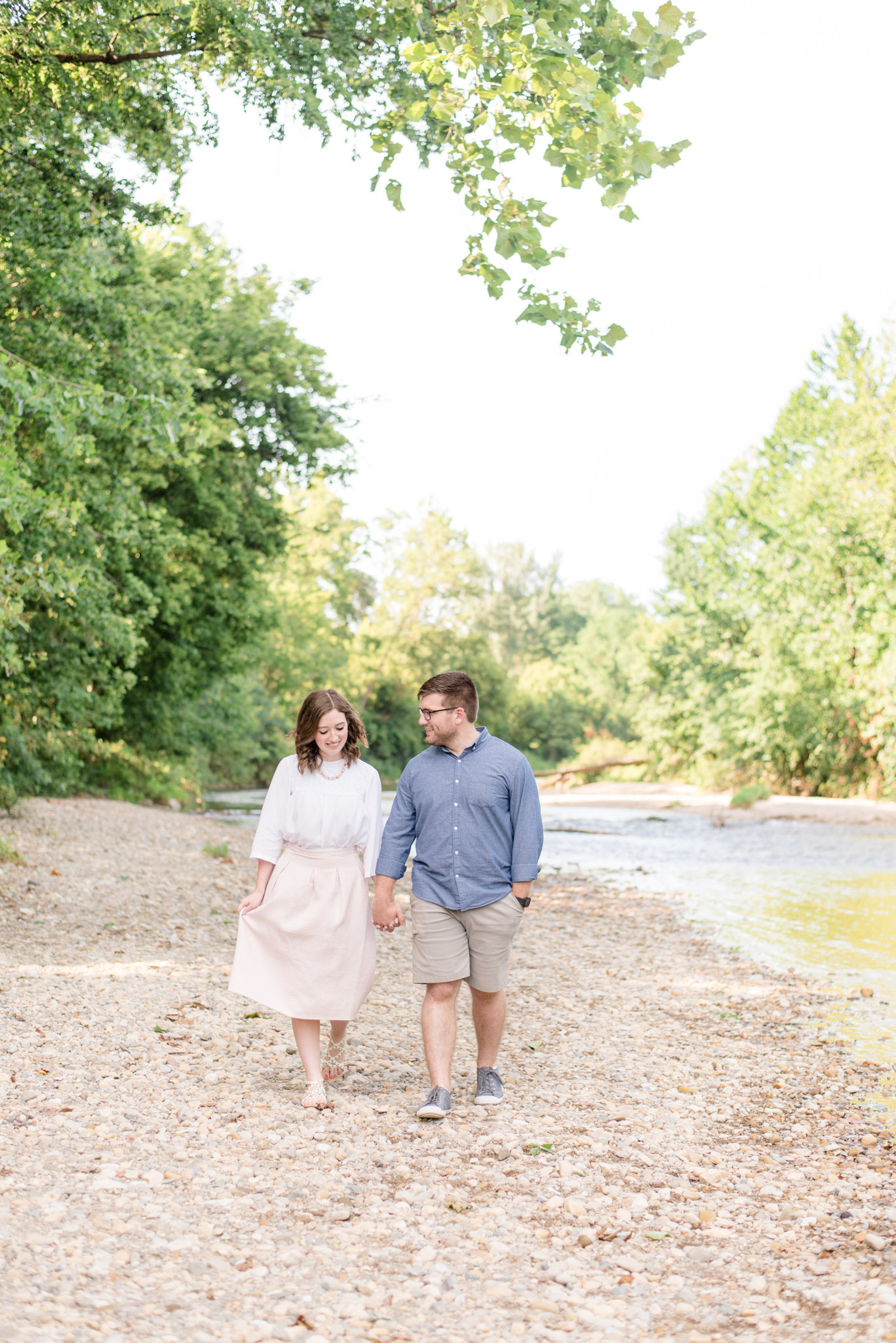 Husband and wife walk along riverbank.