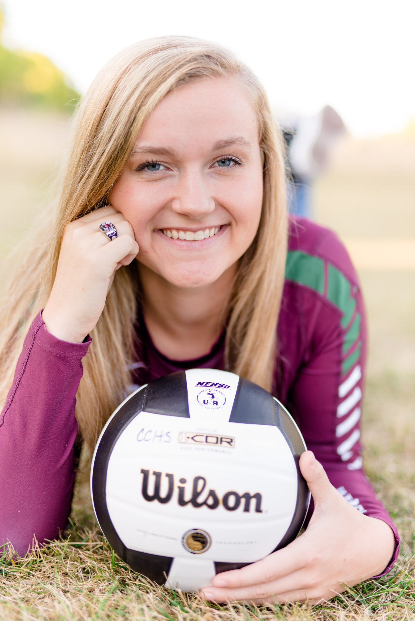 High school senior lays in field with volleyball