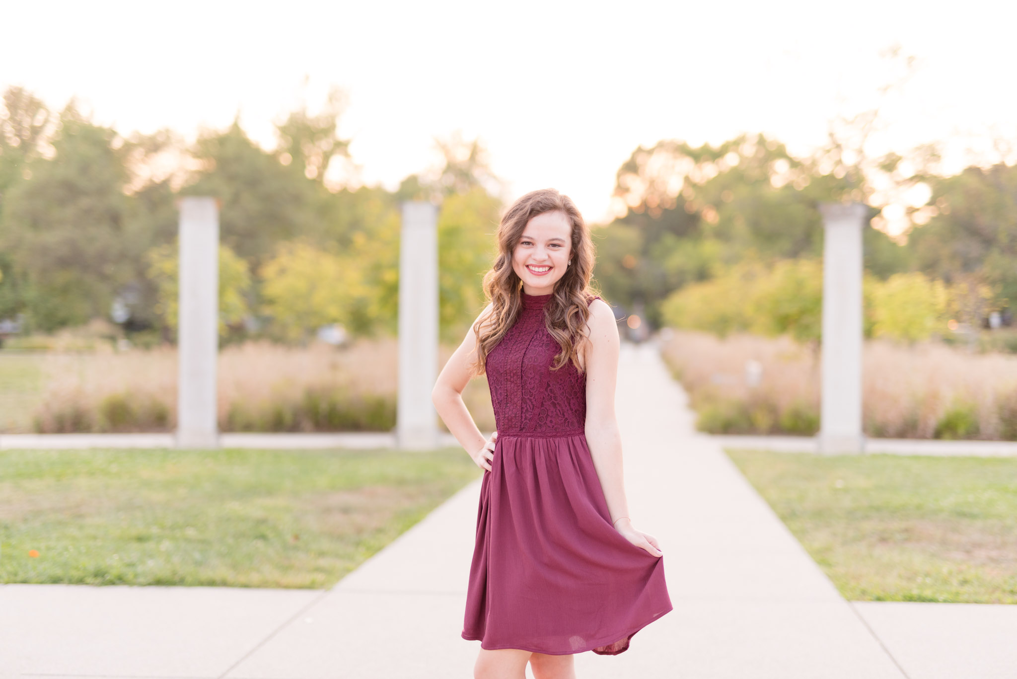 High School Senior smiles at camera at sunset.