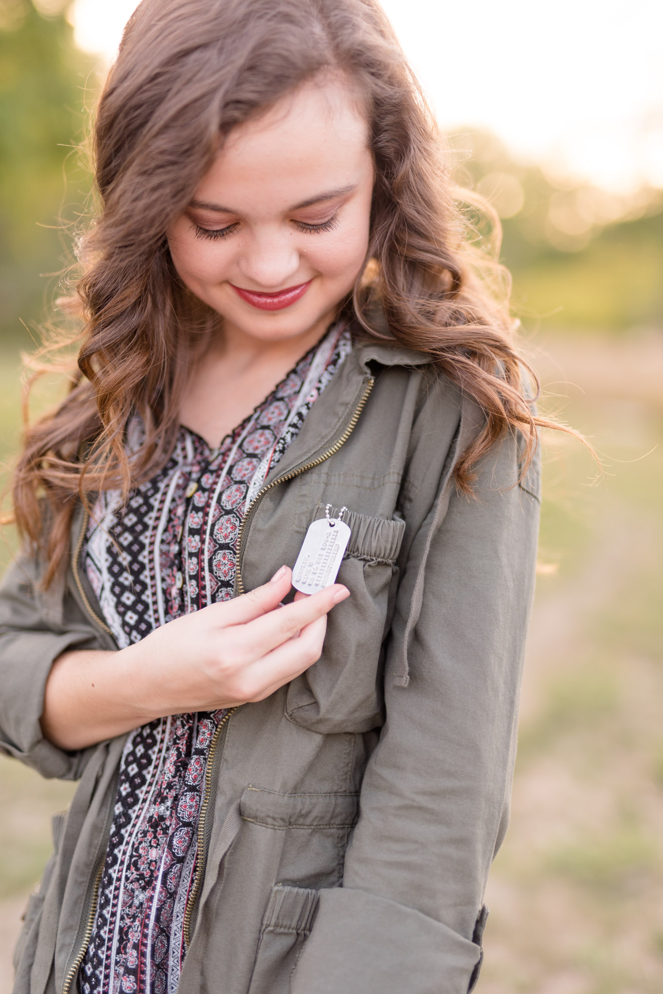 Senior girl looks down at her grandfathers military dogtag.