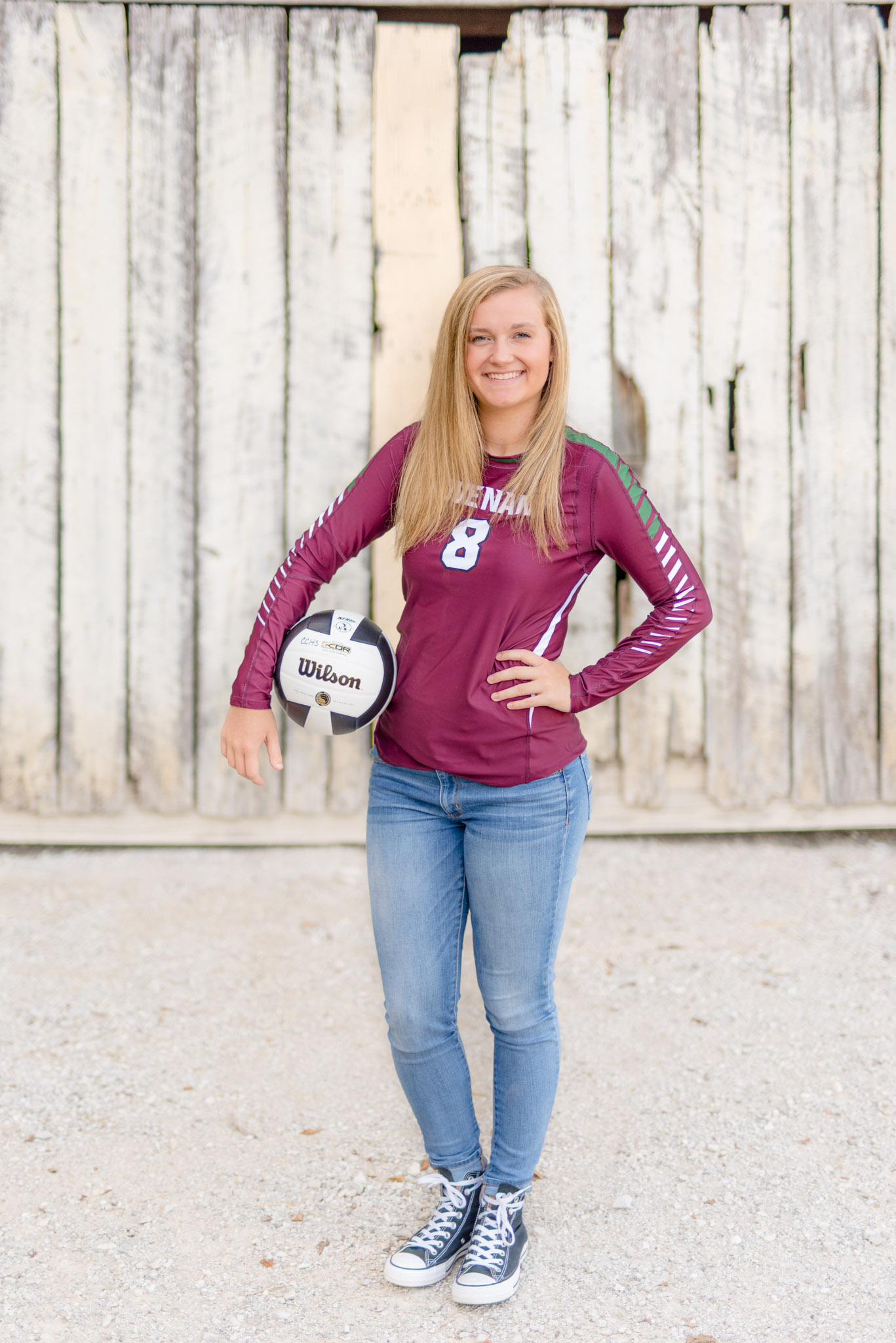 High School senior stand in front of white wall with volleyball
