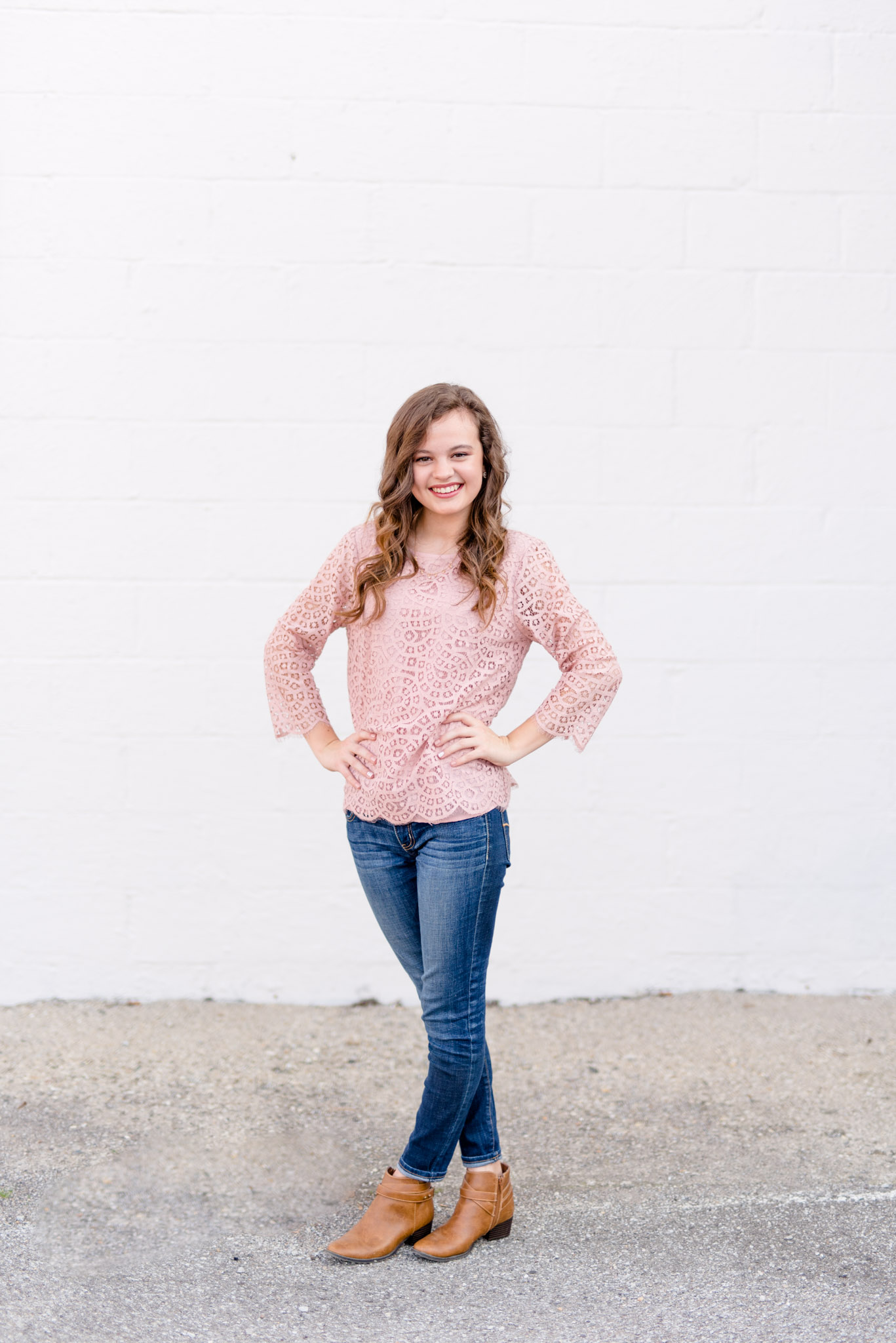 High School senior stands in front of white wall and smiles.