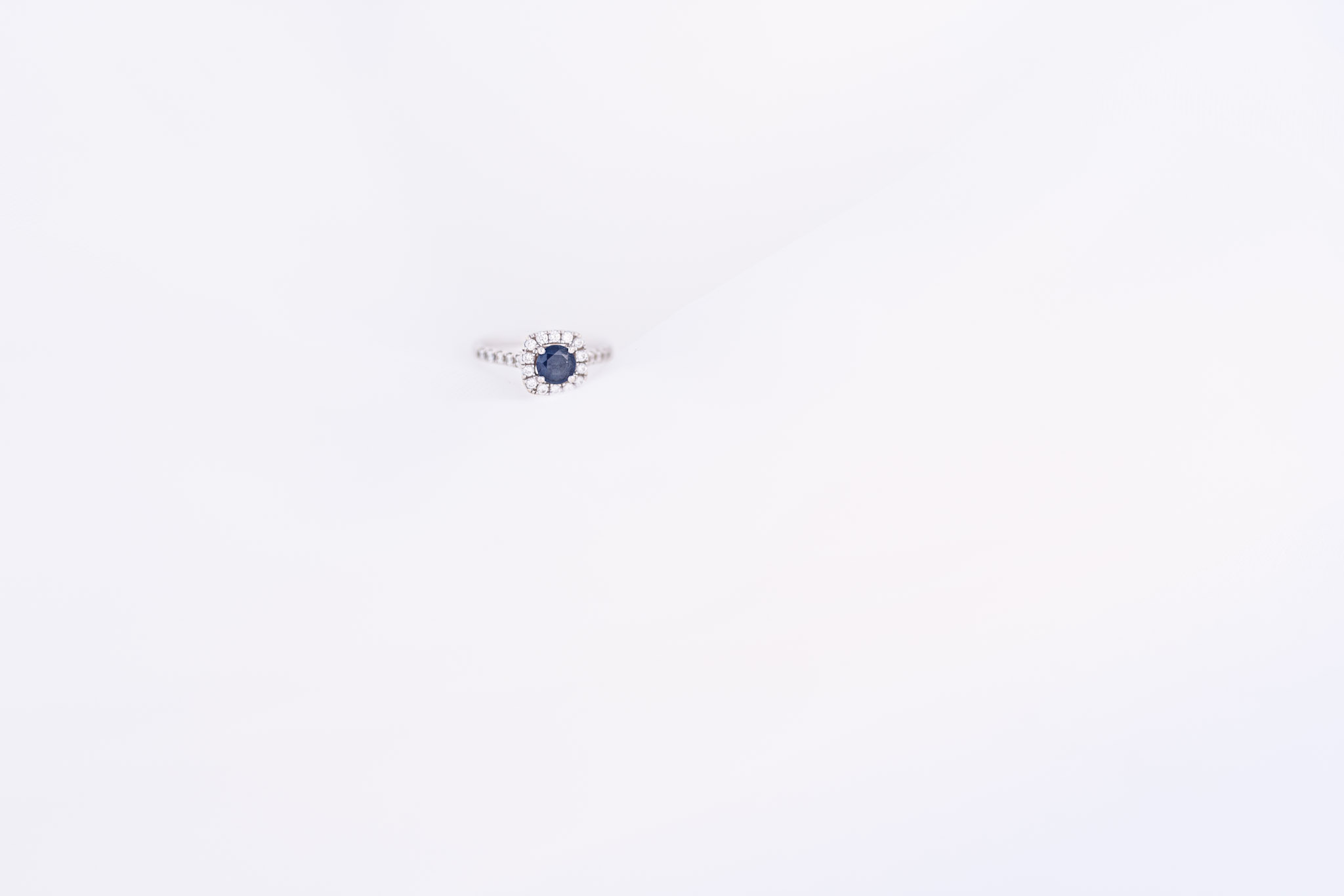 Blue sapphire ring sitting on white cloth.