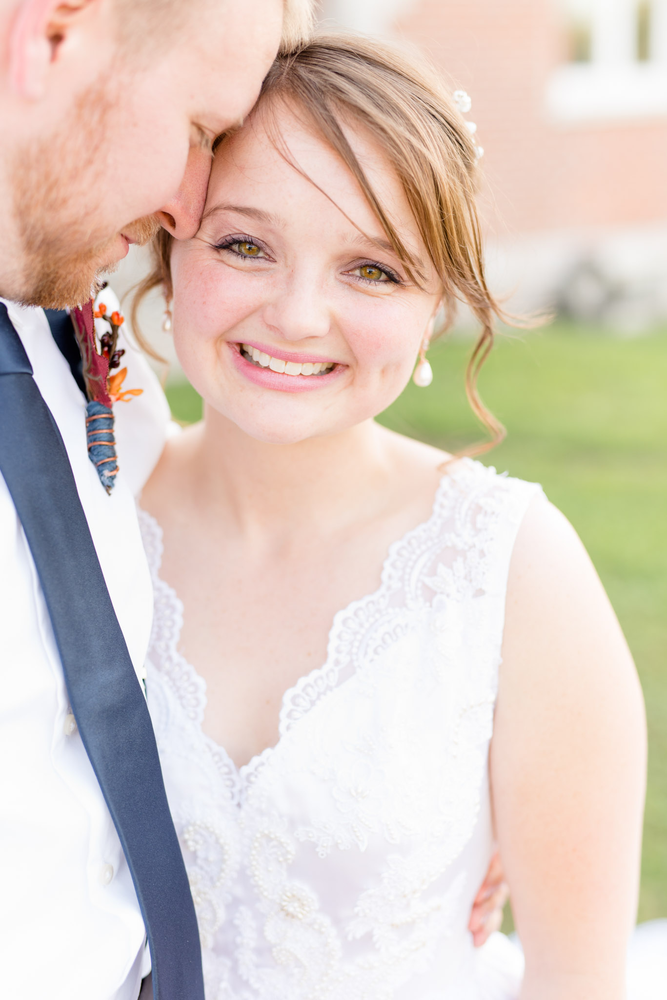 Bride Smiles at Camera while Groom Hugs Her