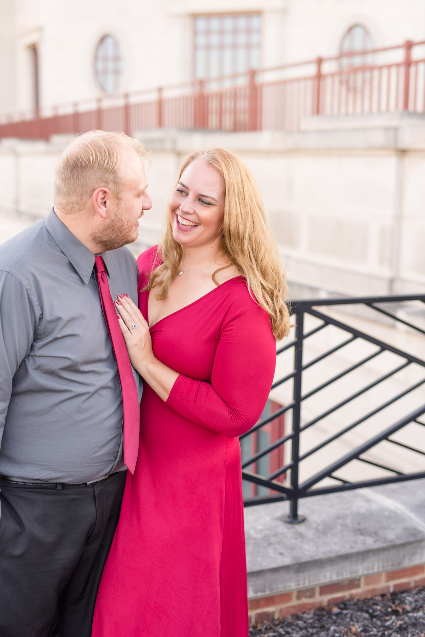 Engaged couple laughs in urban setting.