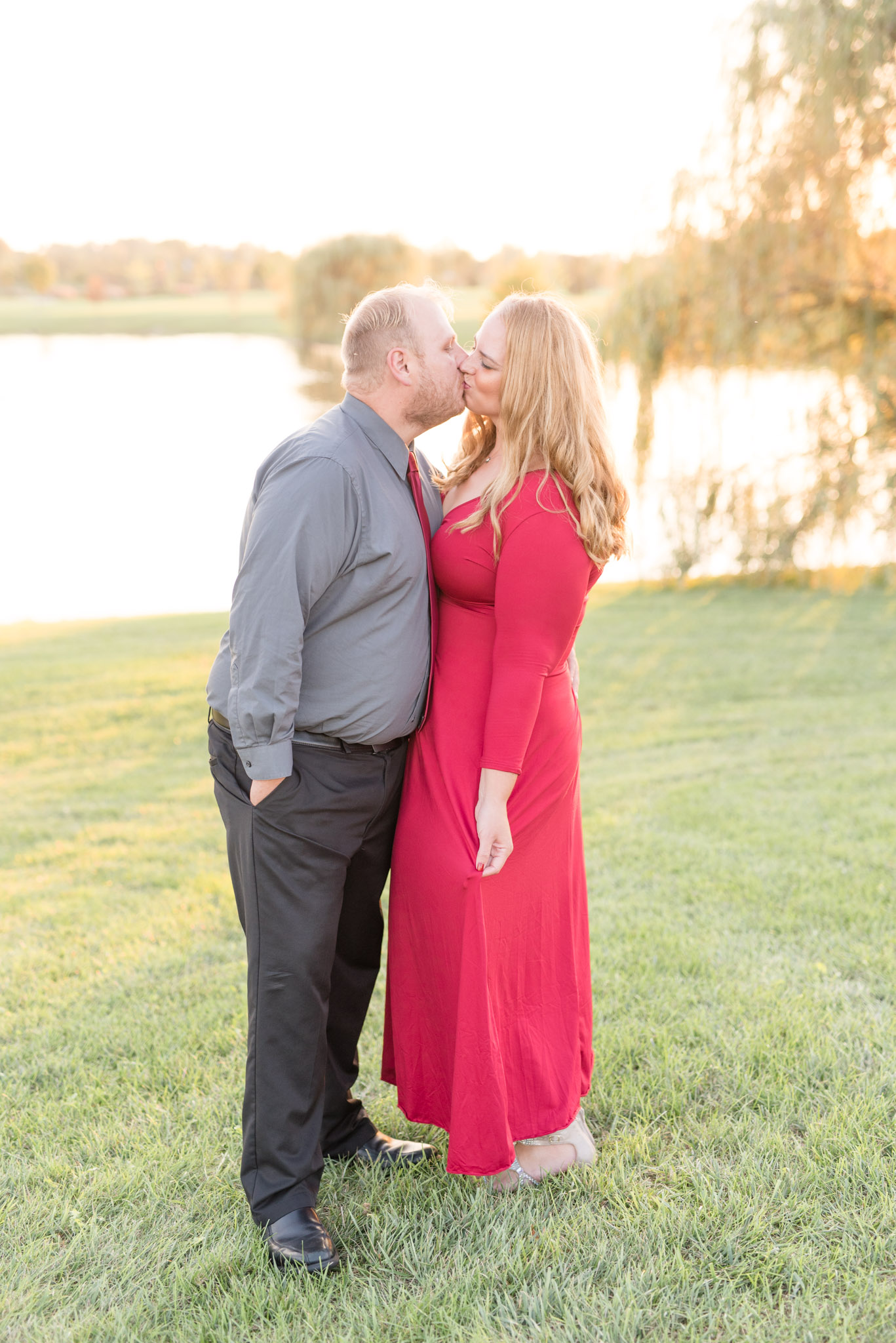 Man and Woman kiss in from of lake at sunset.