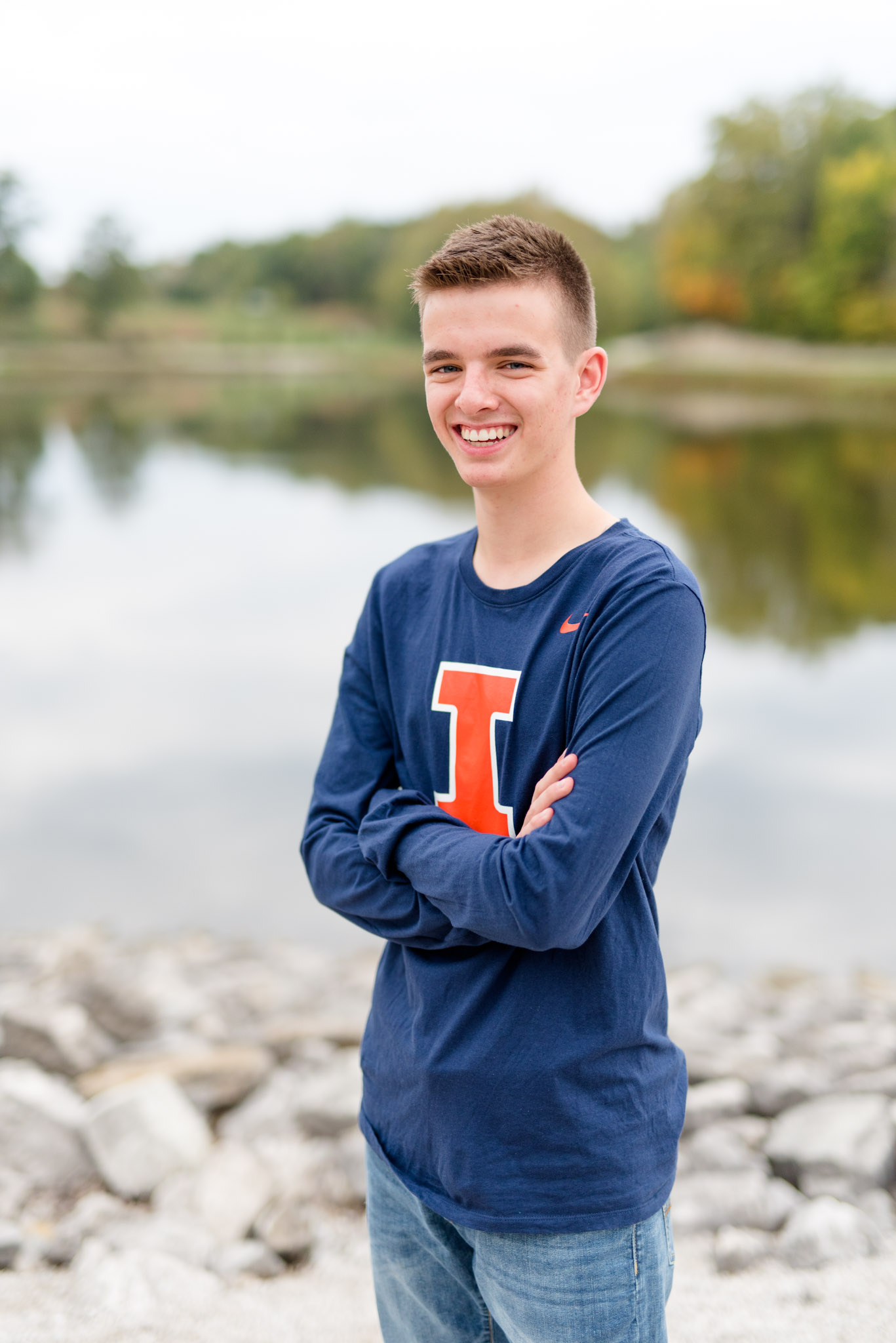 Senior guys smiles in front of lake.