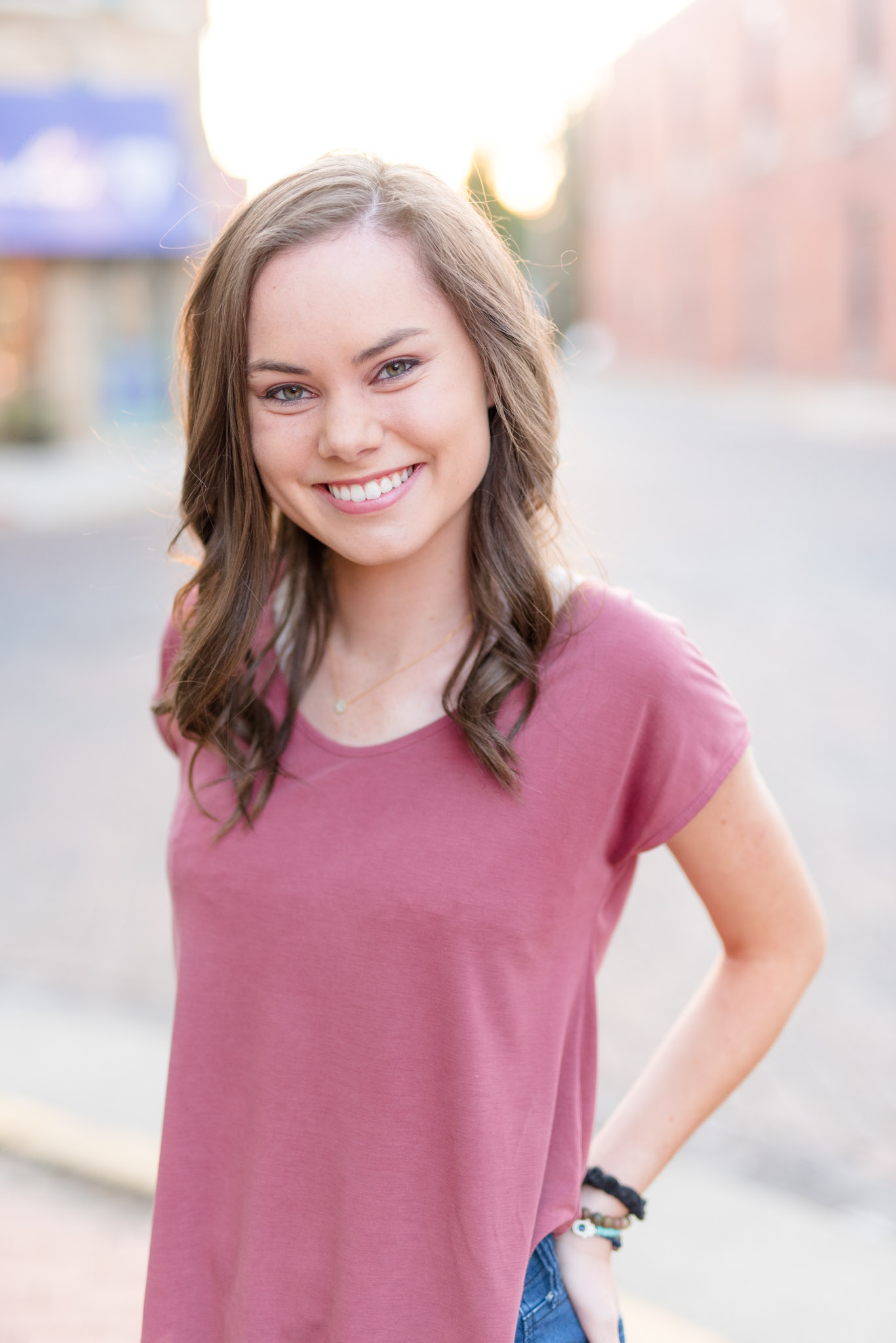 Senior girl smiles during downtown sunset.