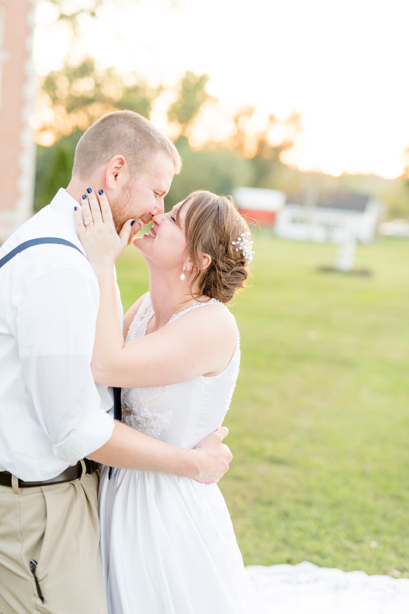 Bride and groom laugh as the kiss at sunset.