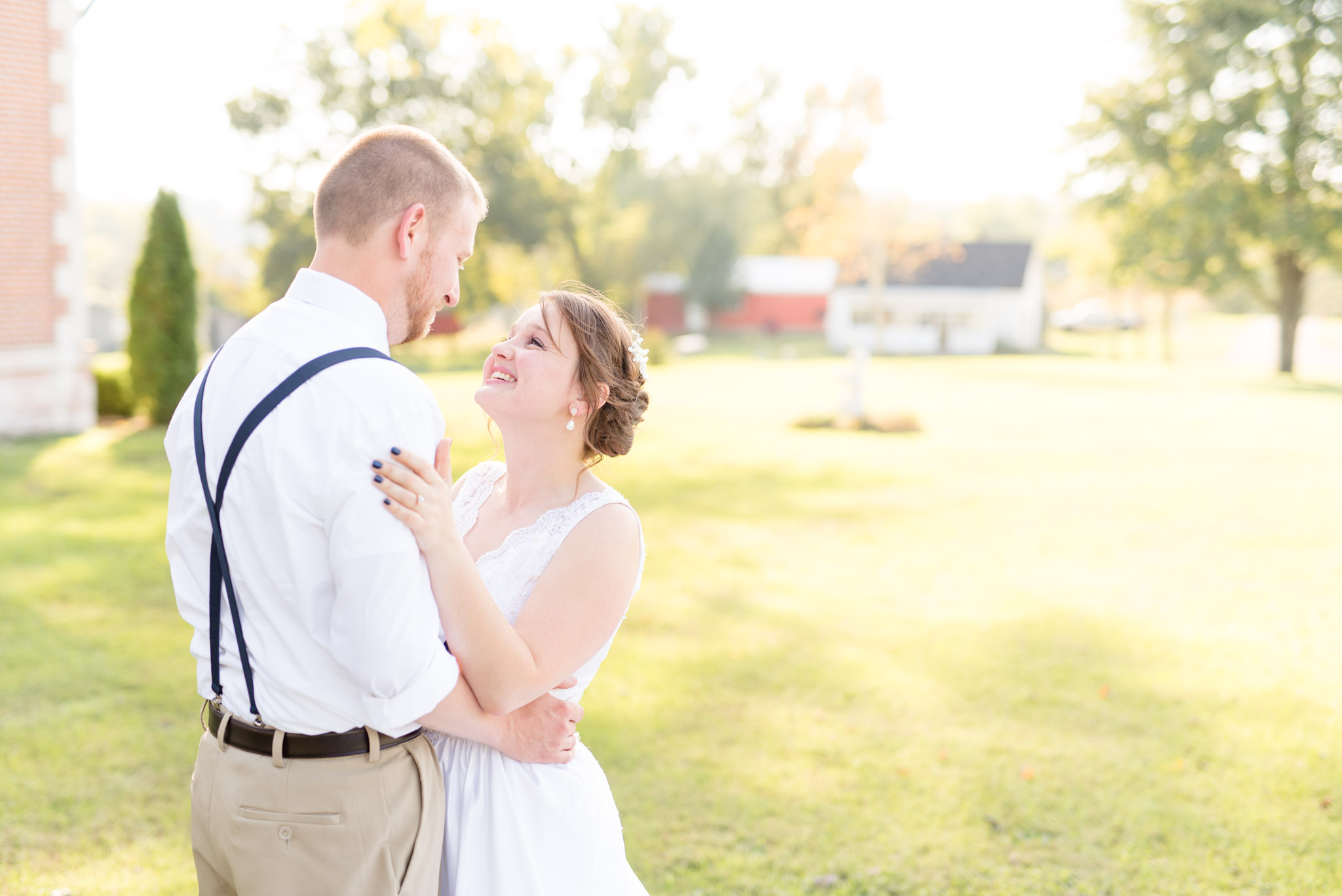 Bride and Groom laugh on green lawn.