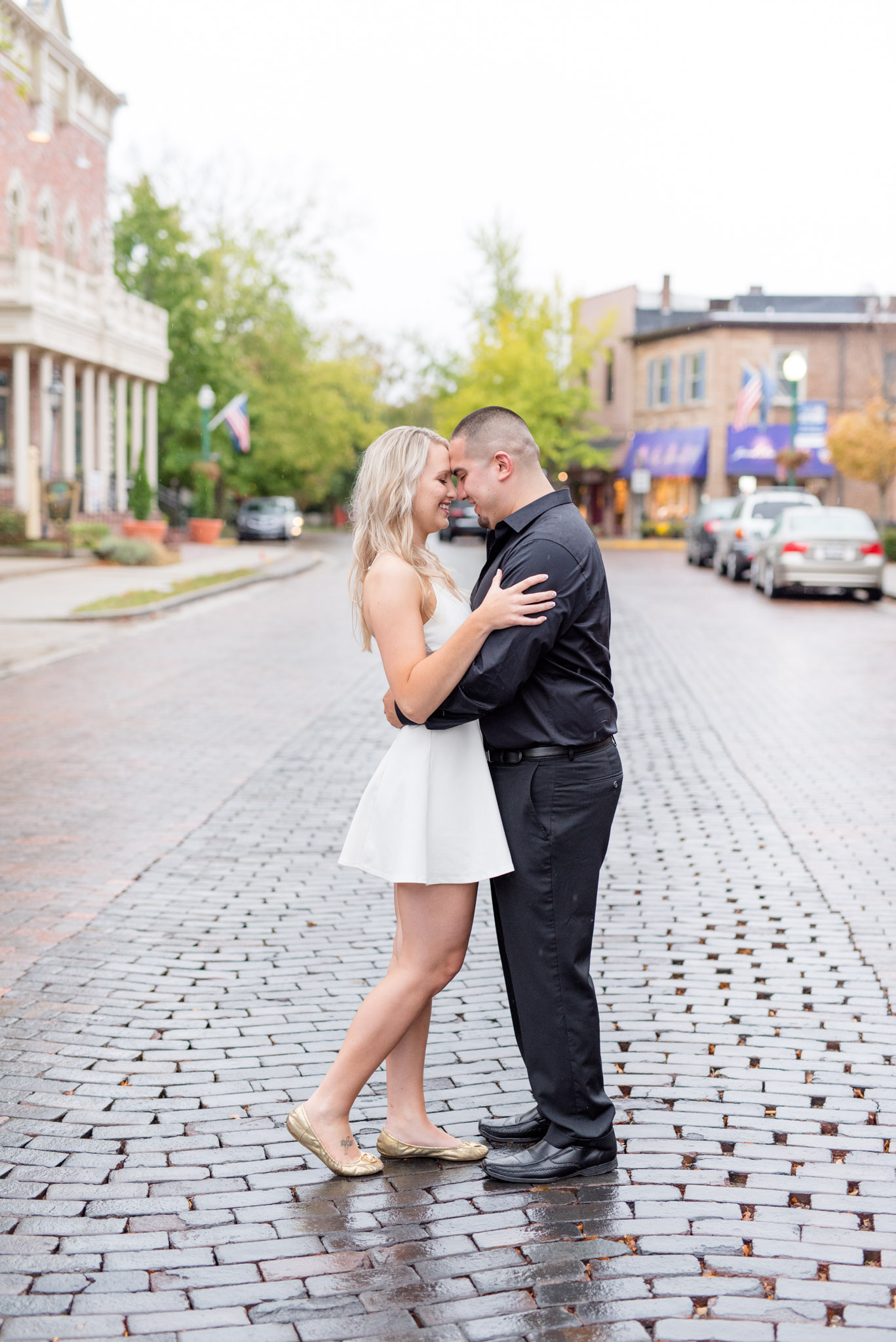 Bride and groom hug on brick street.