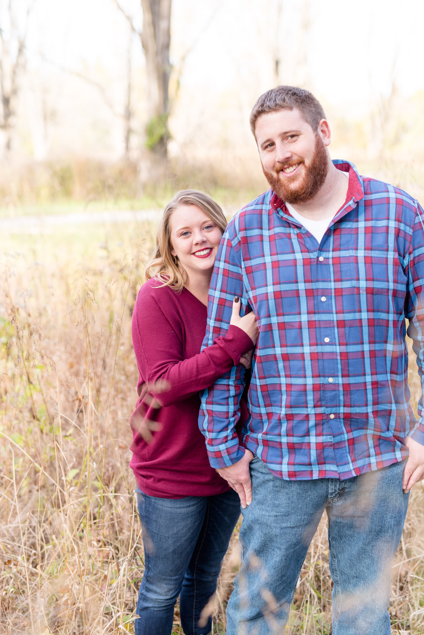 Couple smiles at camera in field.