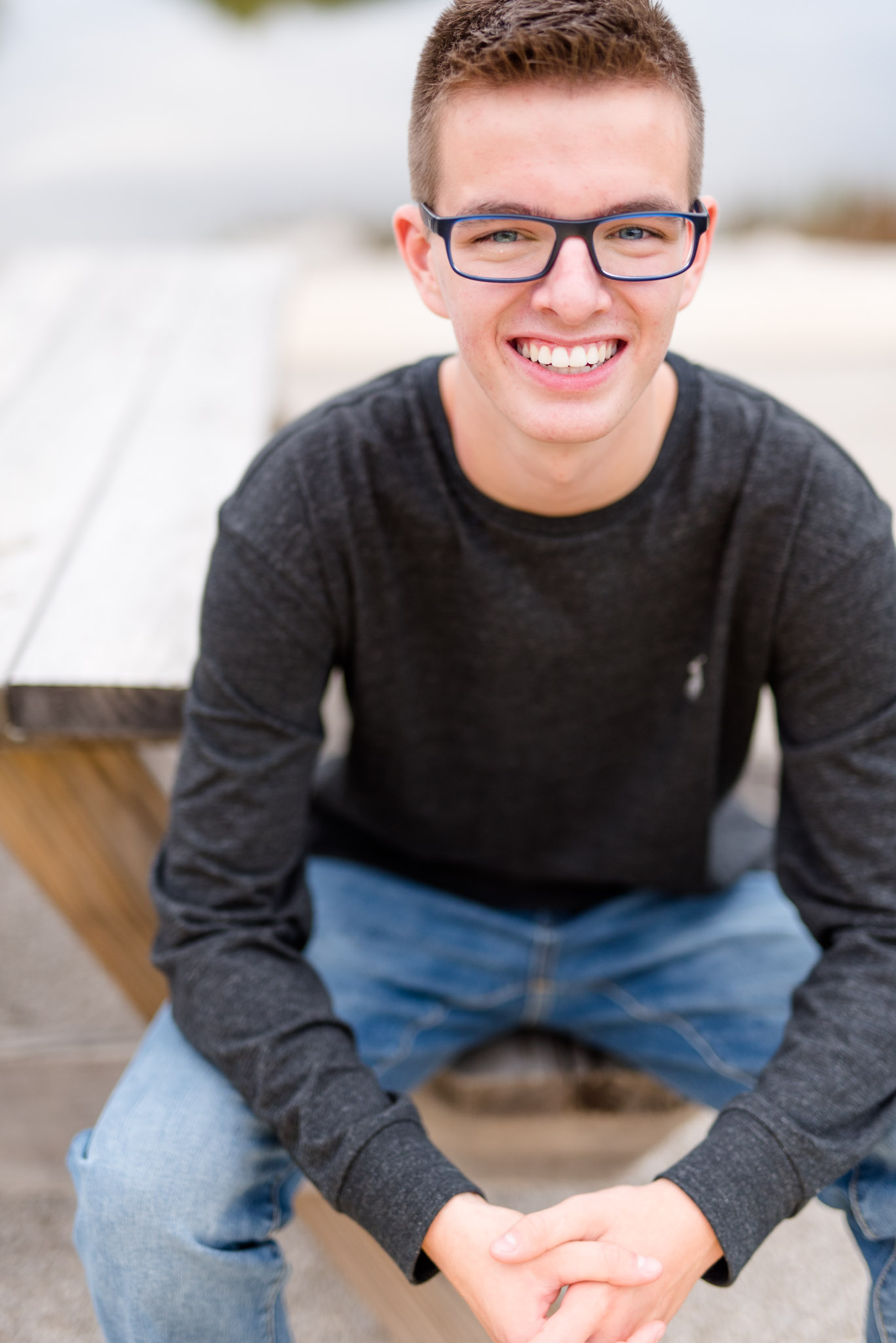 High school senior smiles at camera from bench.