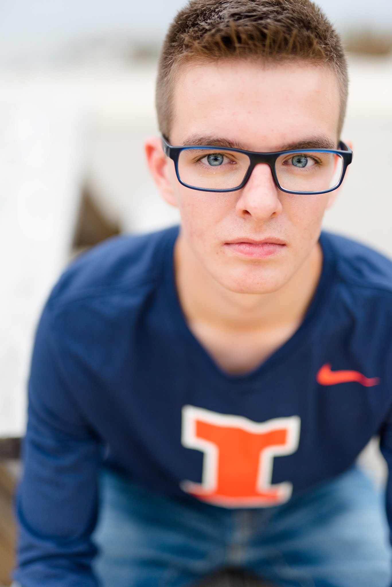 Senior guy with glasses sits on bench.