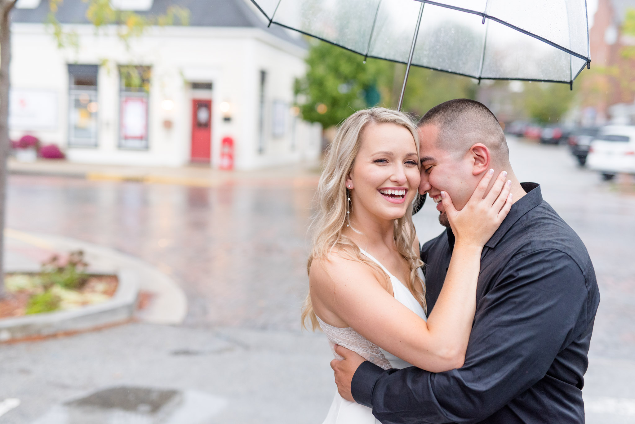 Bride laughs towards camera while groom holds umbrella.