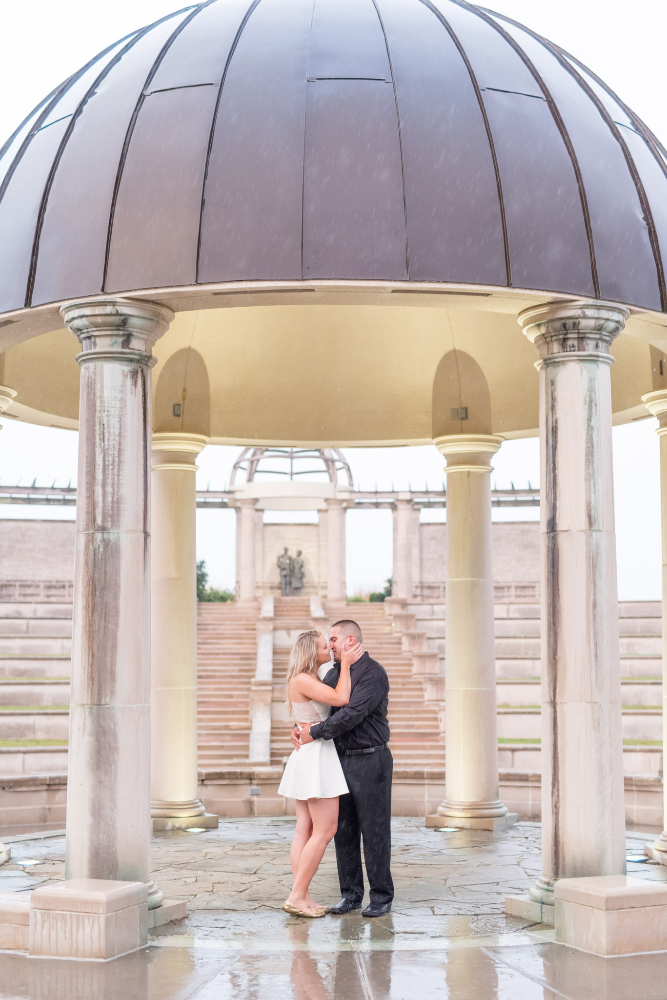 Engaged couple kiss while in ampitheatre.