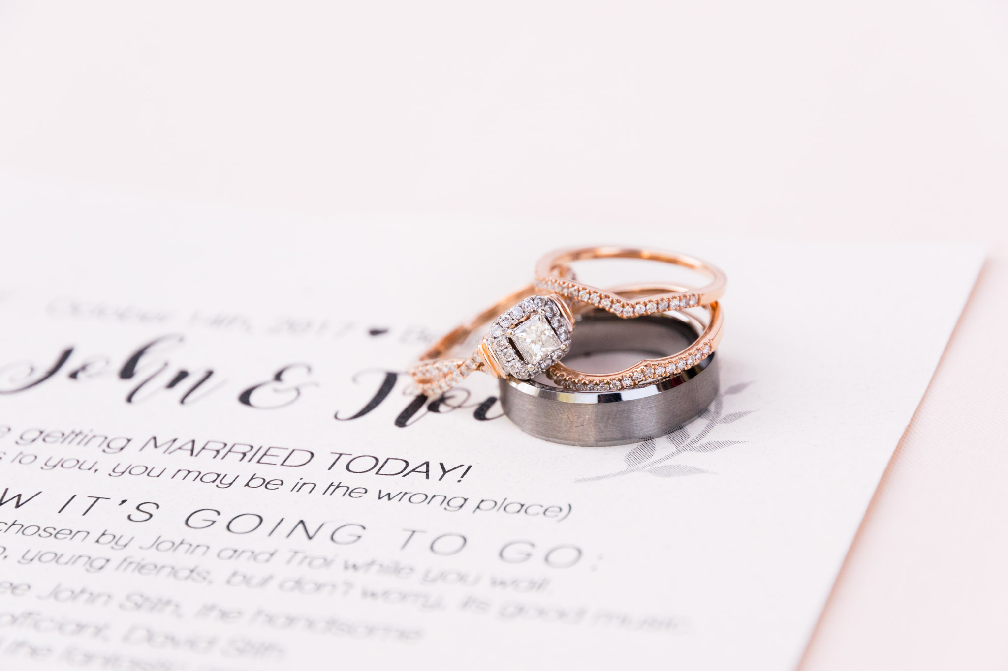 Engagement Ring and Wedding bands sit on wedding program.