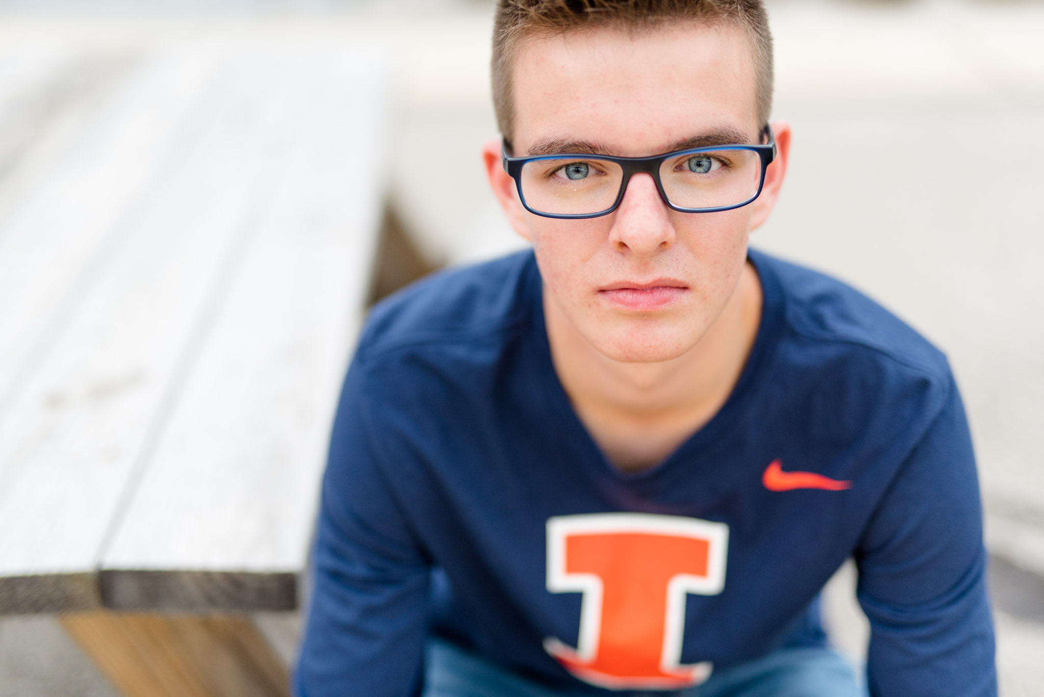 Senior guy looks at camera while sitting on bench.