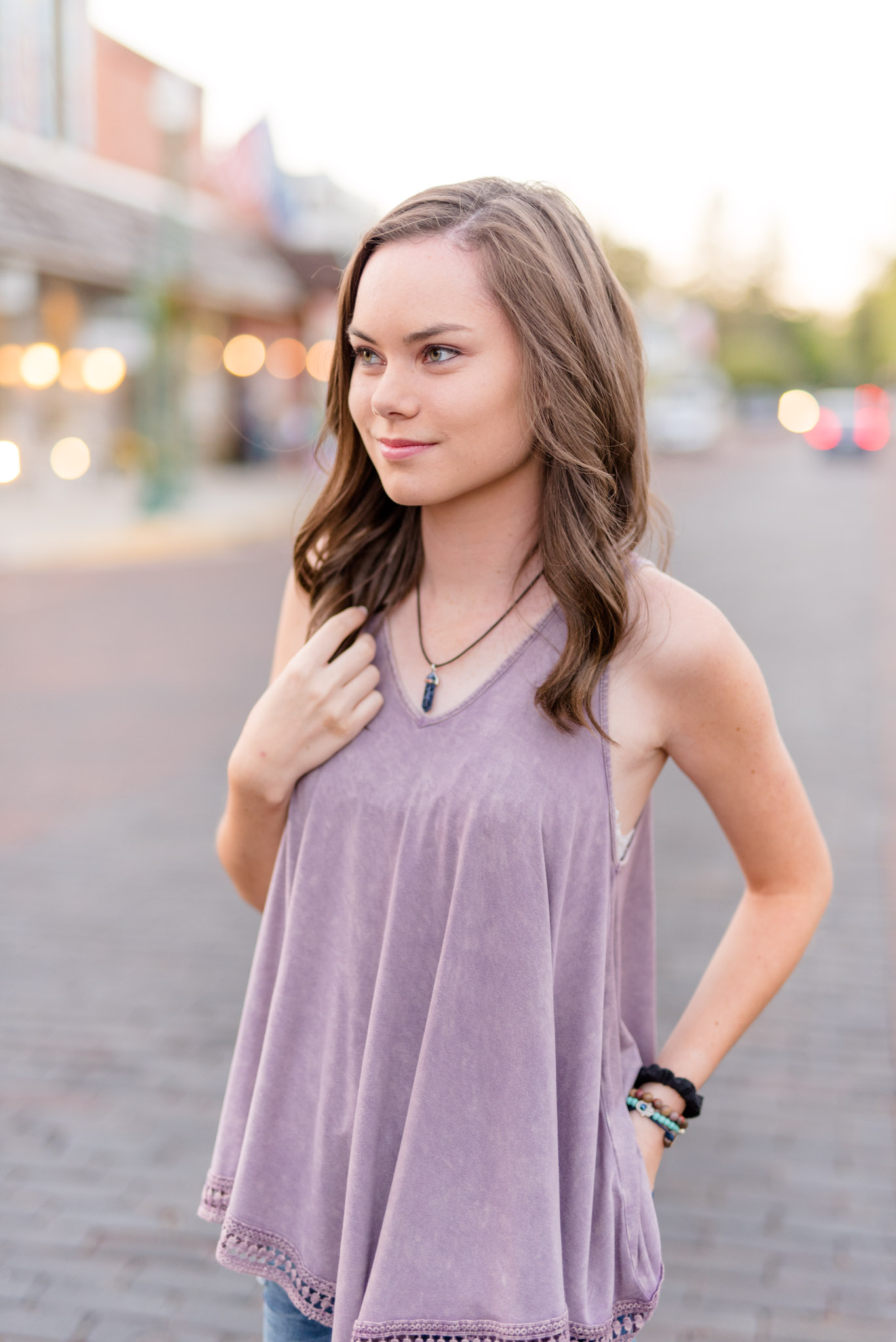 Senior girl looks off camera in downtown setting.