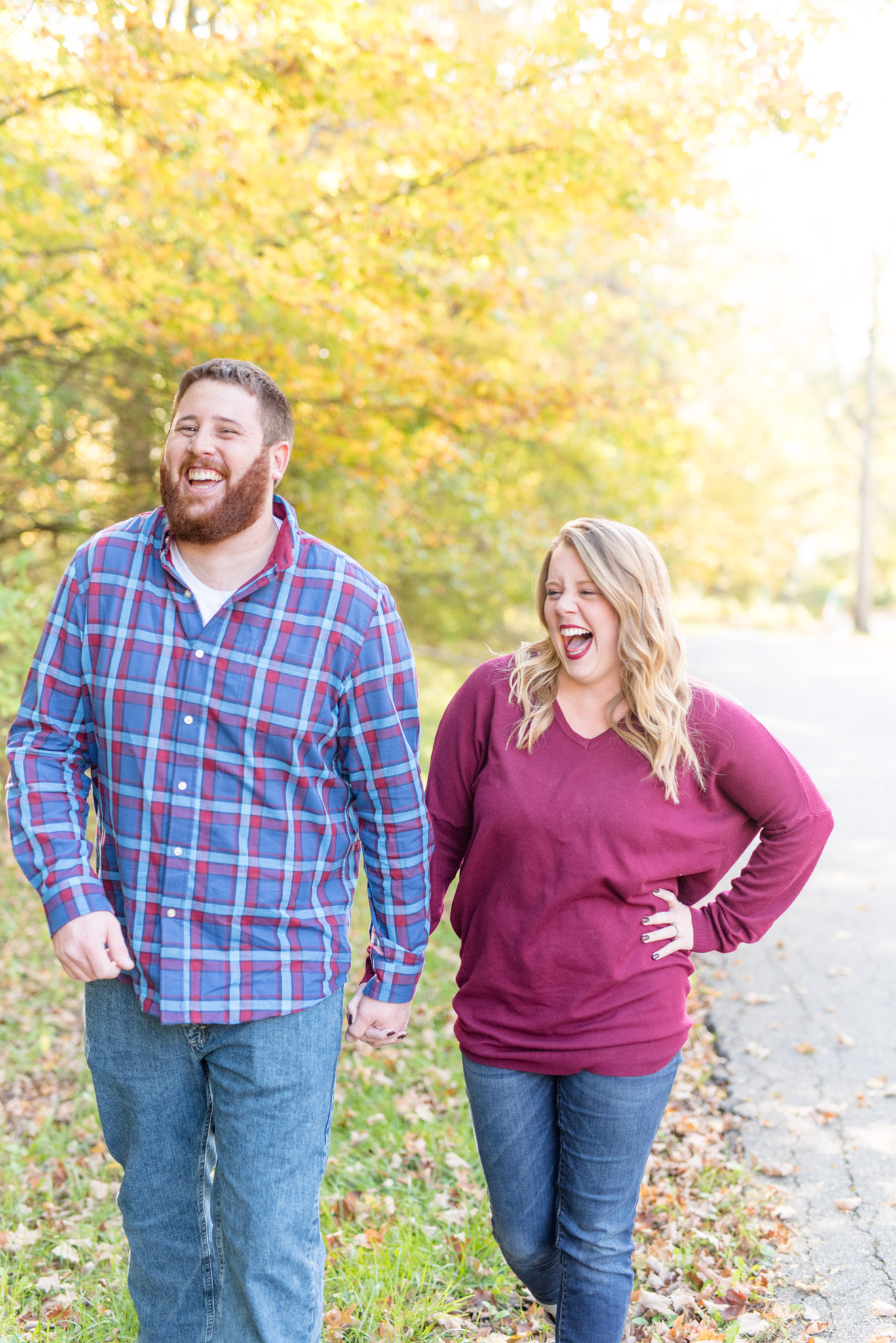Couple laughs as they walk on forest path.