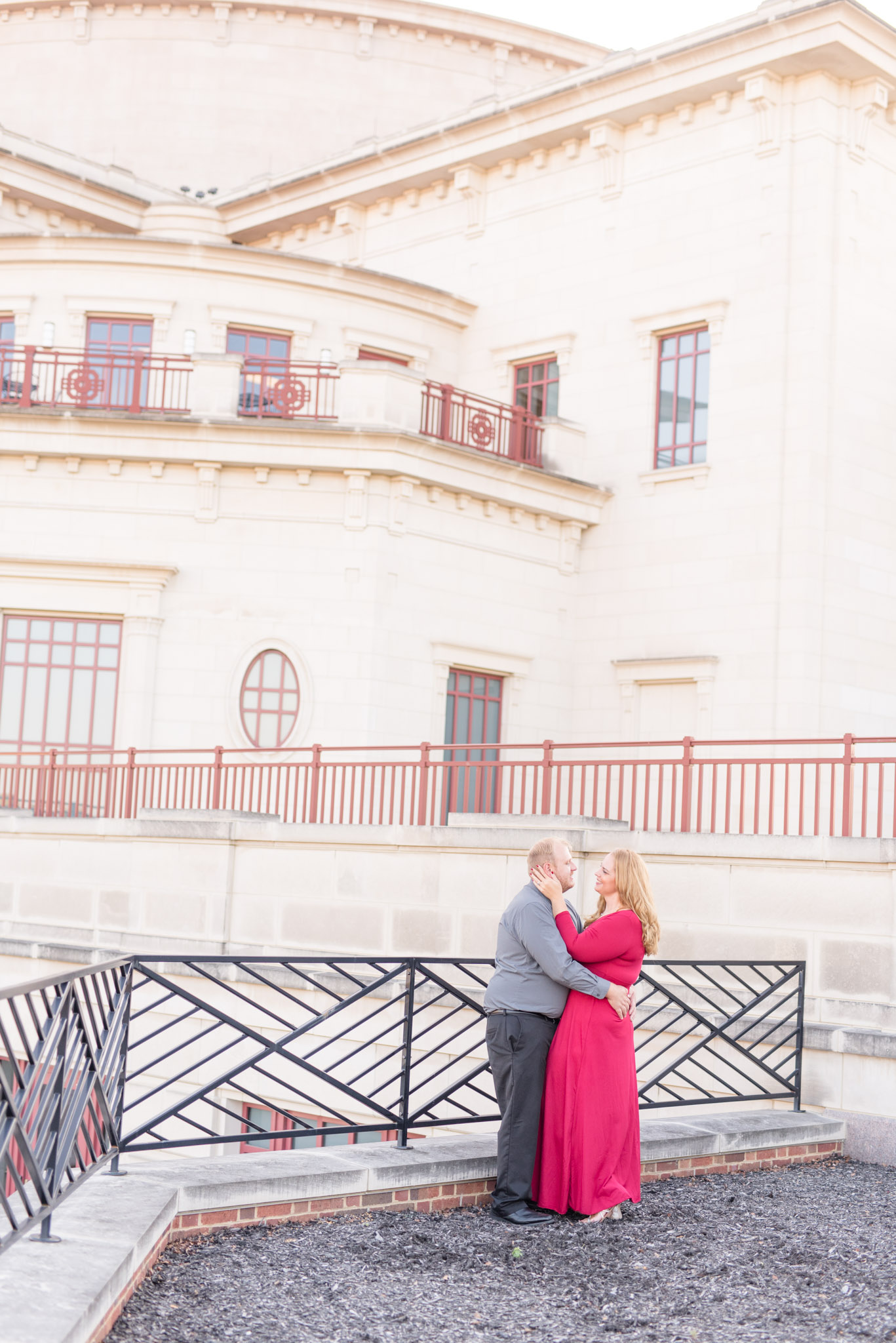 Engaged couple stand in front of white building.