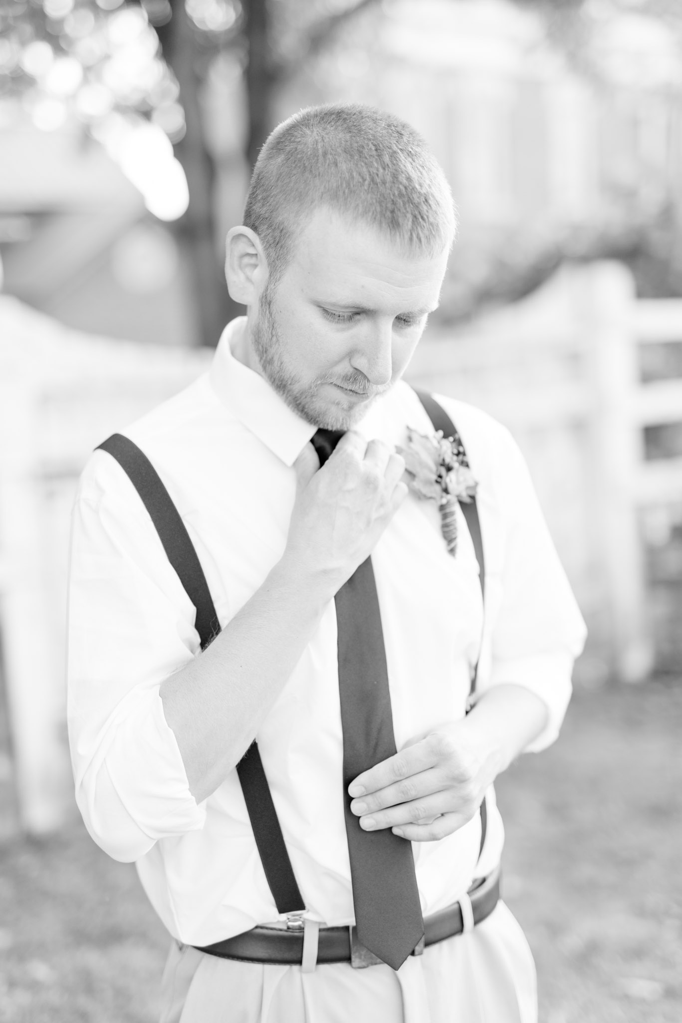 Groom straightens tie and looks down.