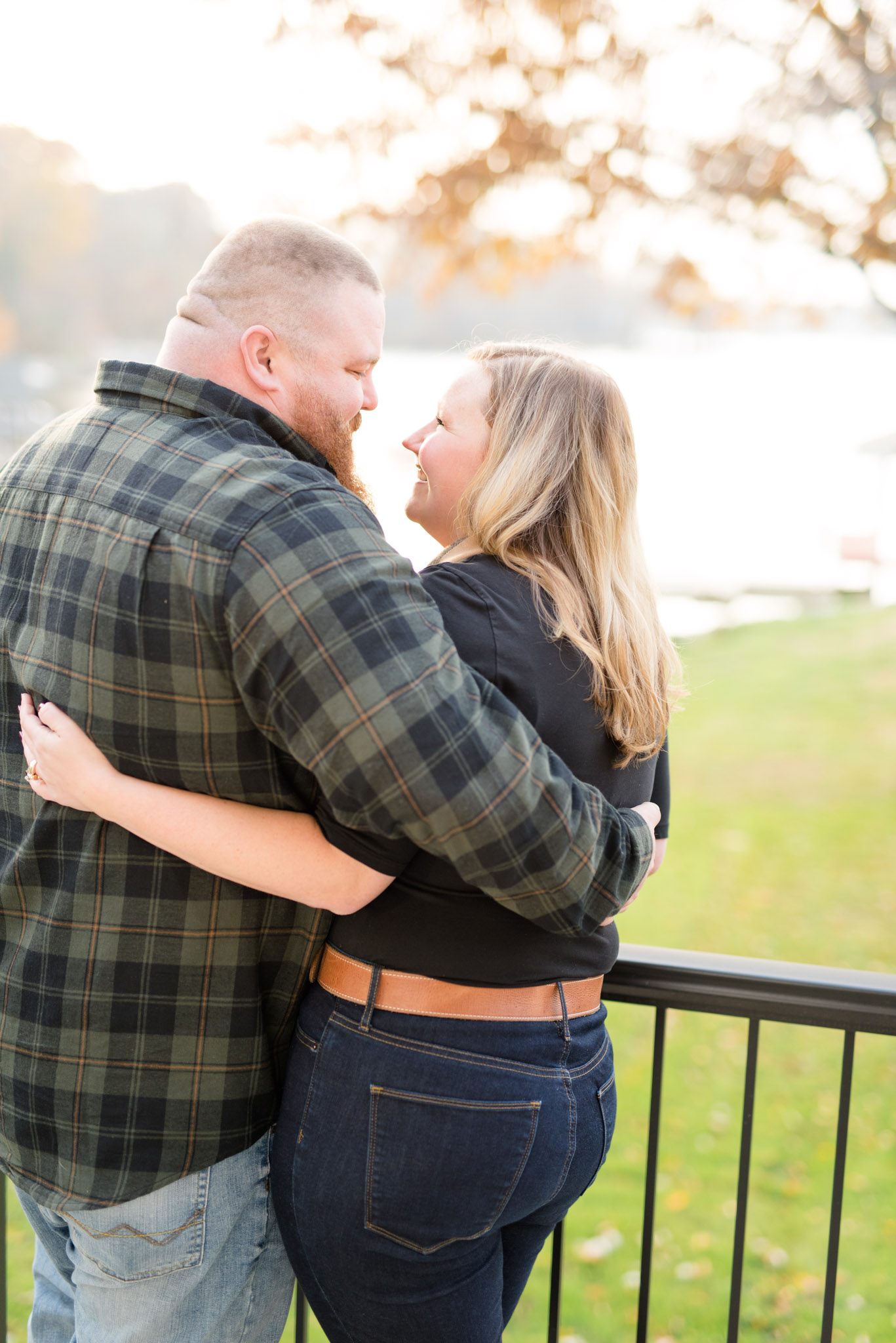 Engaged bride and groom hold each other on balcony.