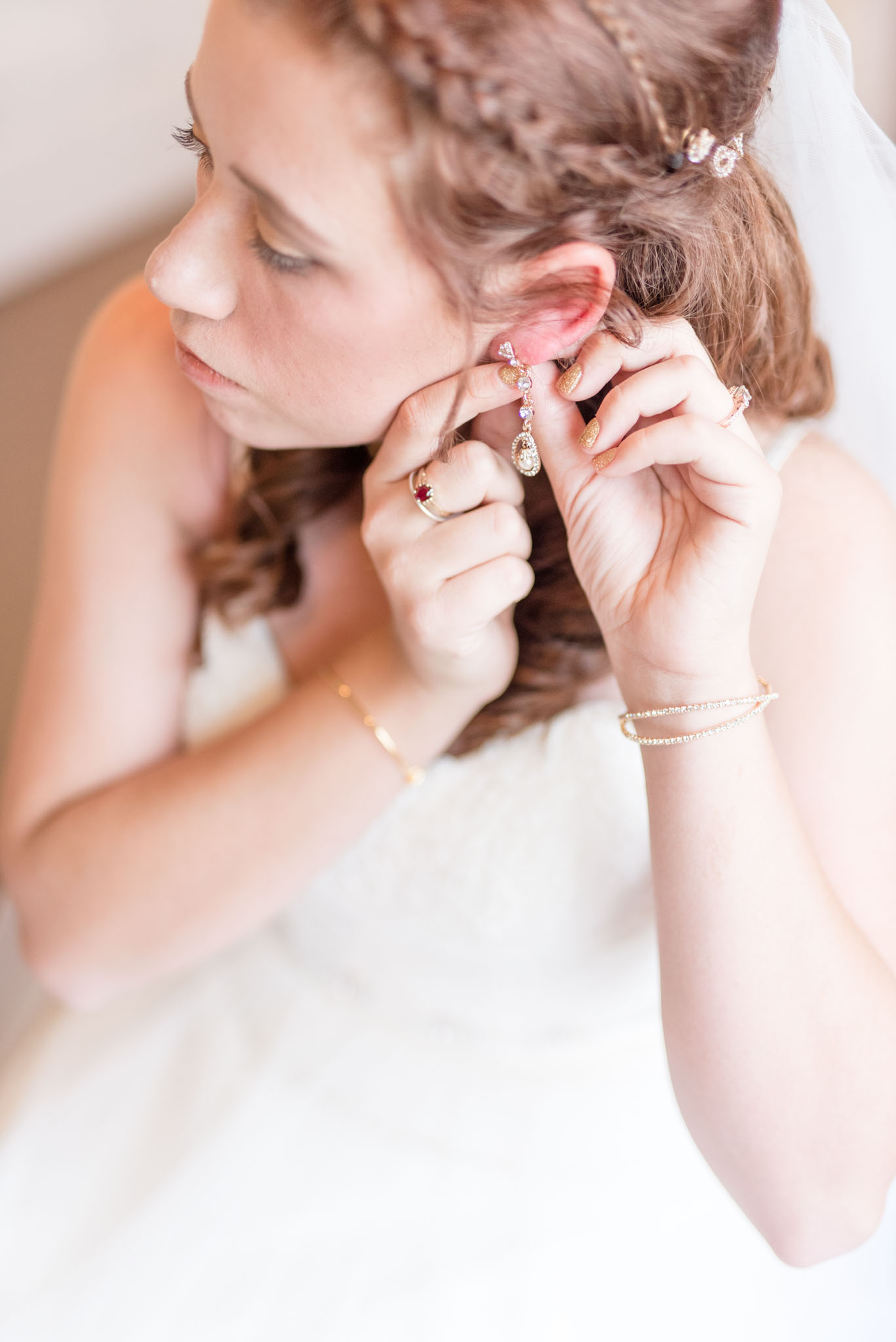 Bride puts on her earrings on her wedding day.