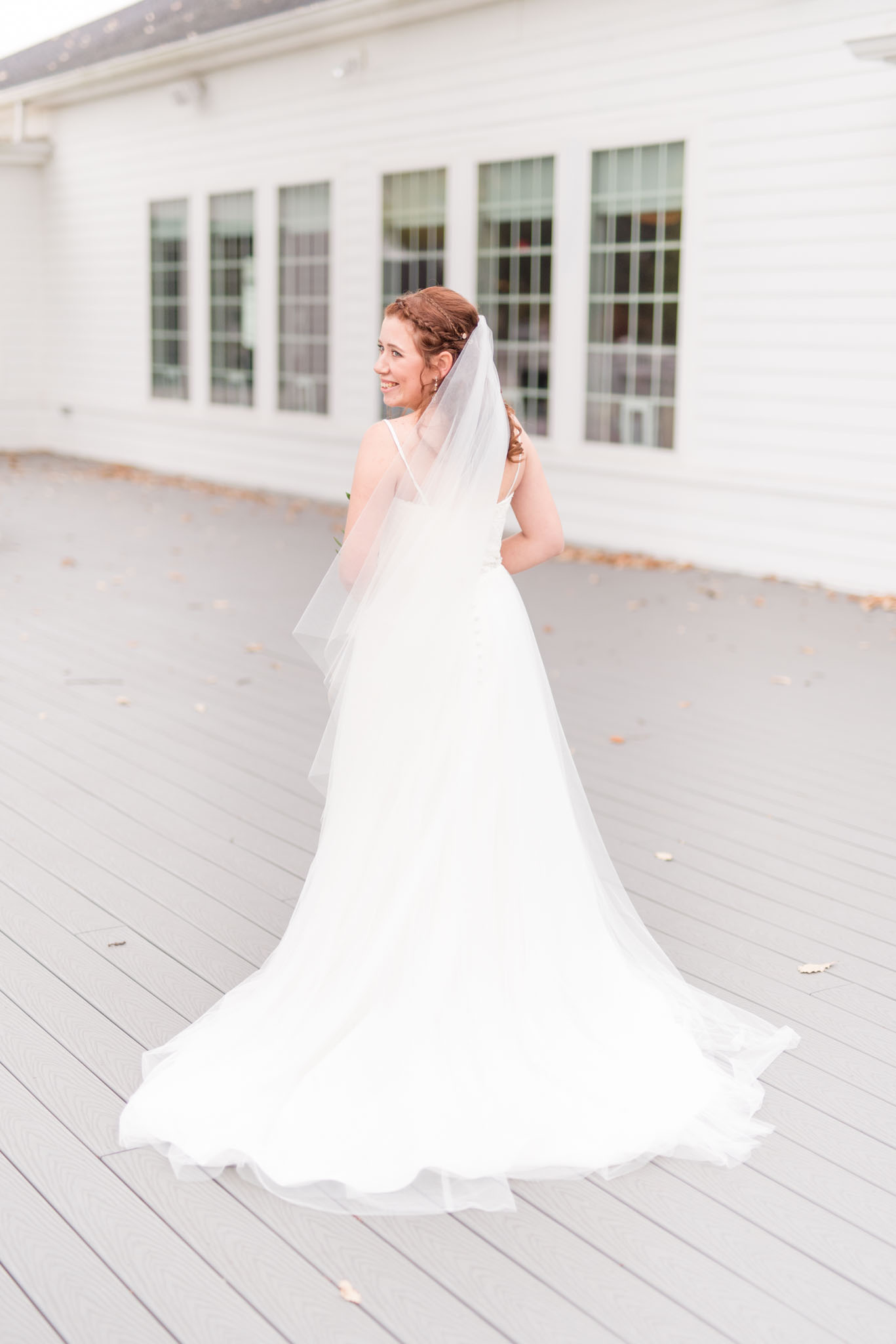 Bride looks over shoulder at white wedding venue.