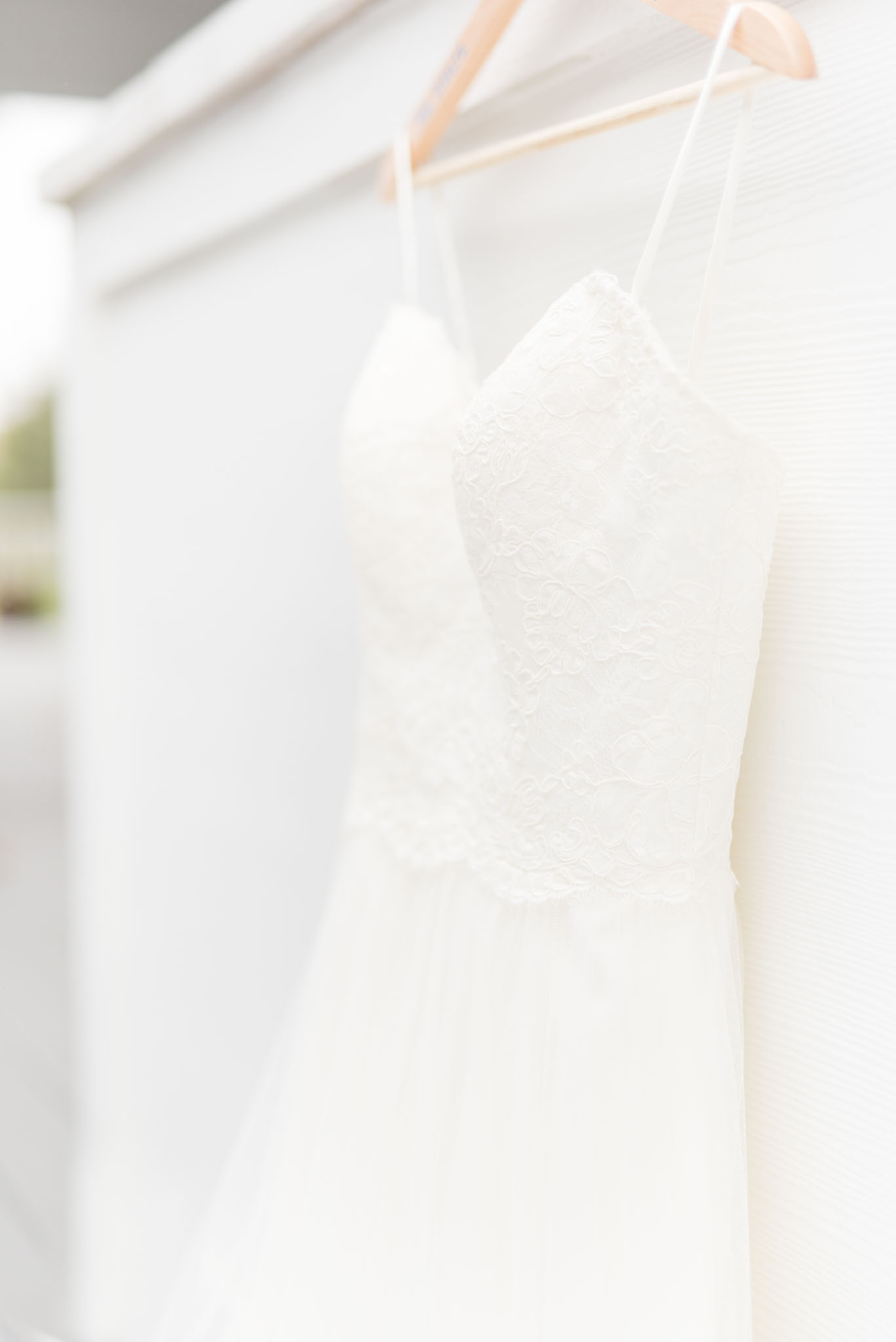 Wedding Dress Hangs on White Wall.
